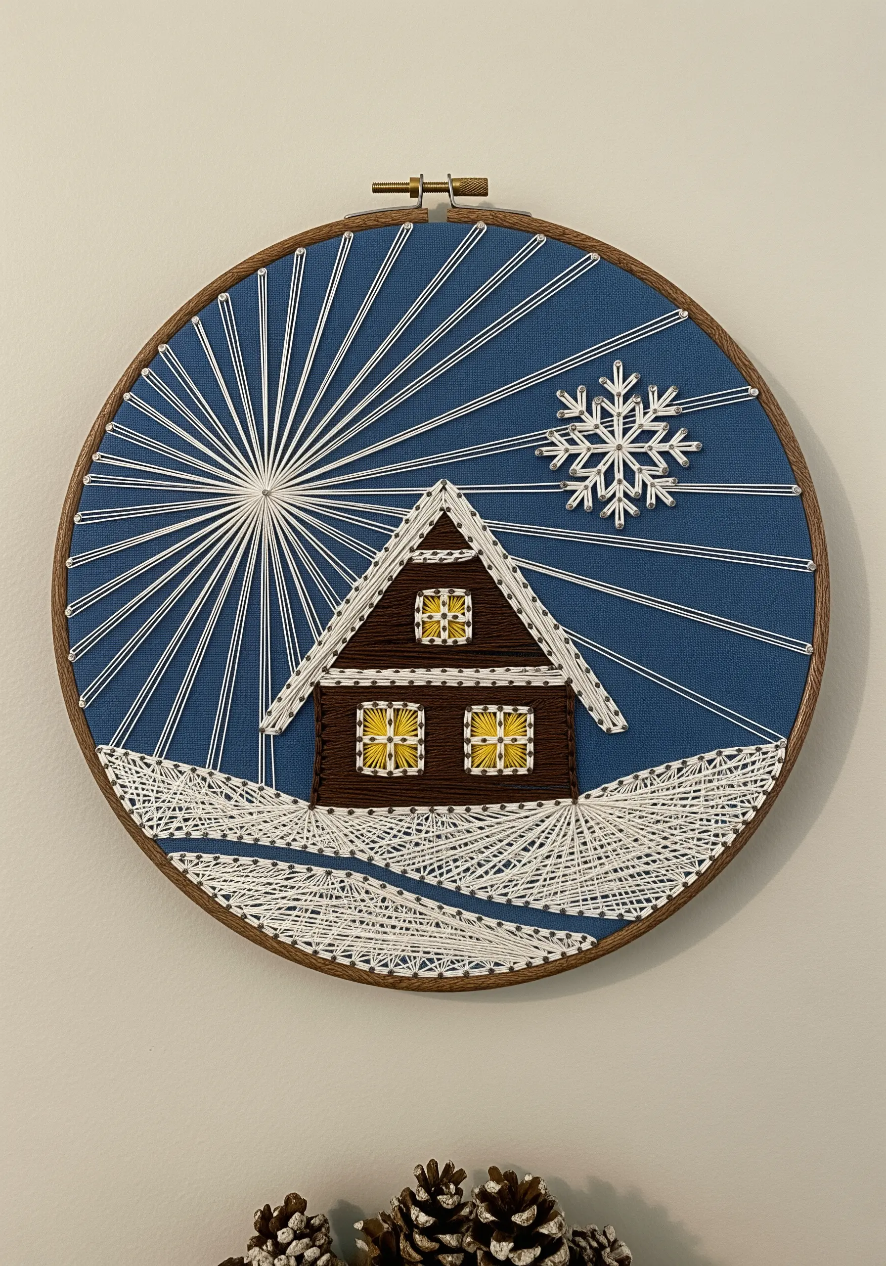 String art winter scene featuring a cabin, horizontal snow, and a sunburst sky.