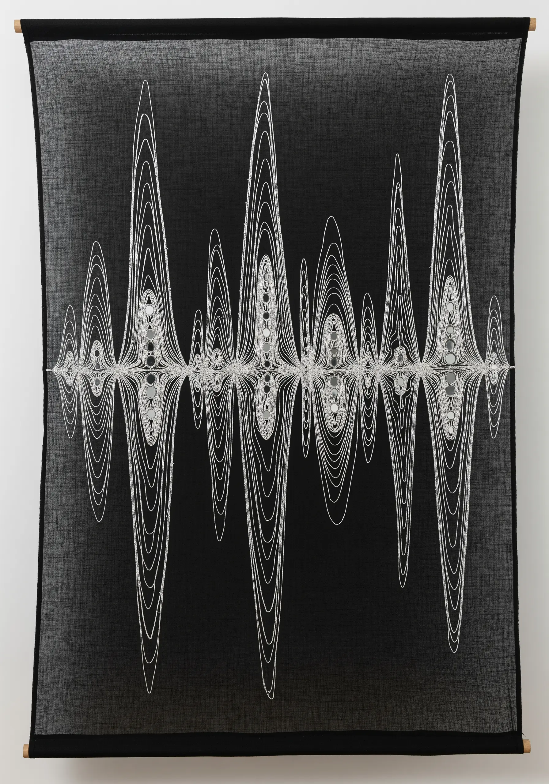 White thread on sheer black fabric creating a complex, symmetrical soundwave pattern.