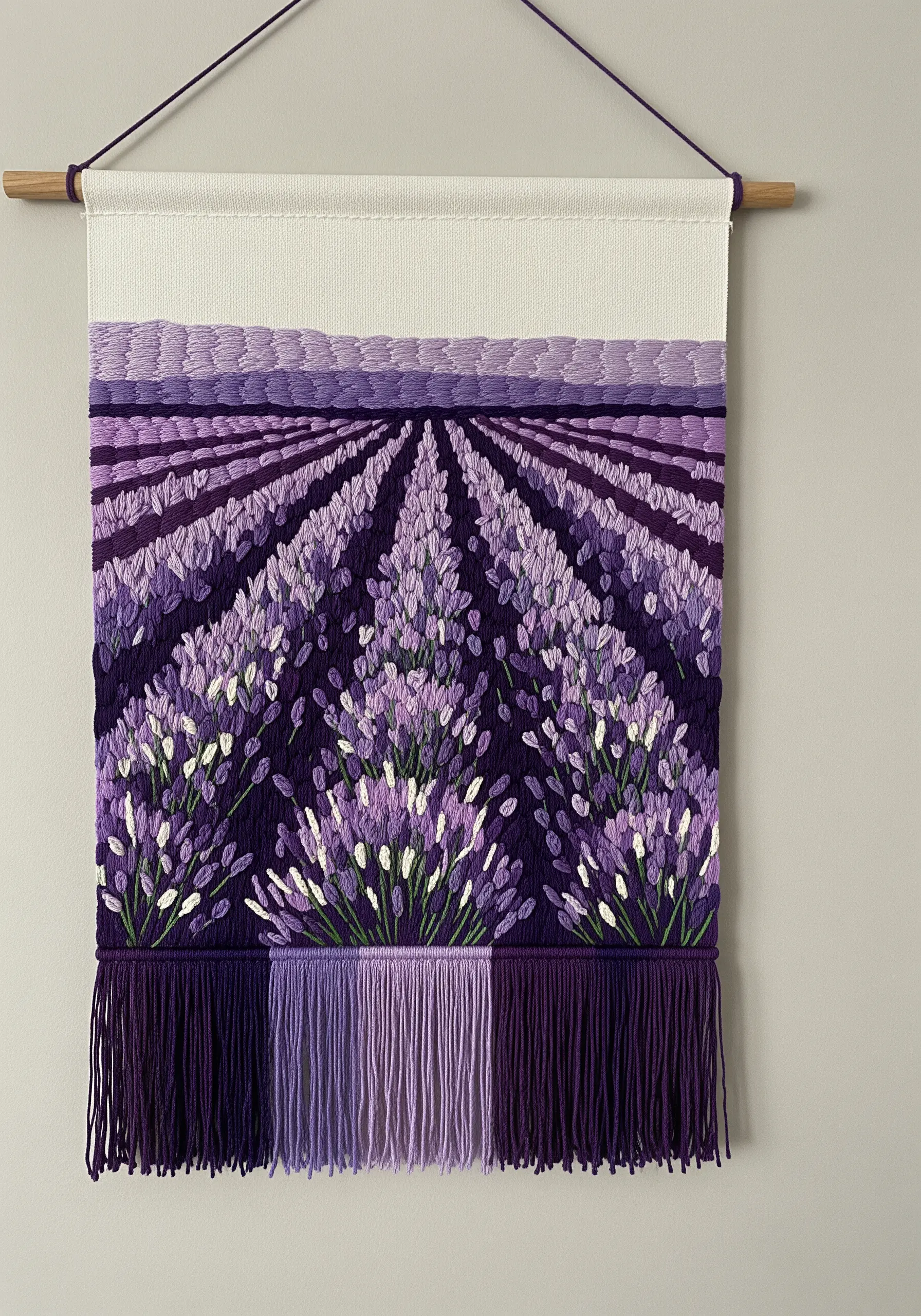 A woven and embroidered wall hanging depicting a textured lavender field with a fringed bottom.