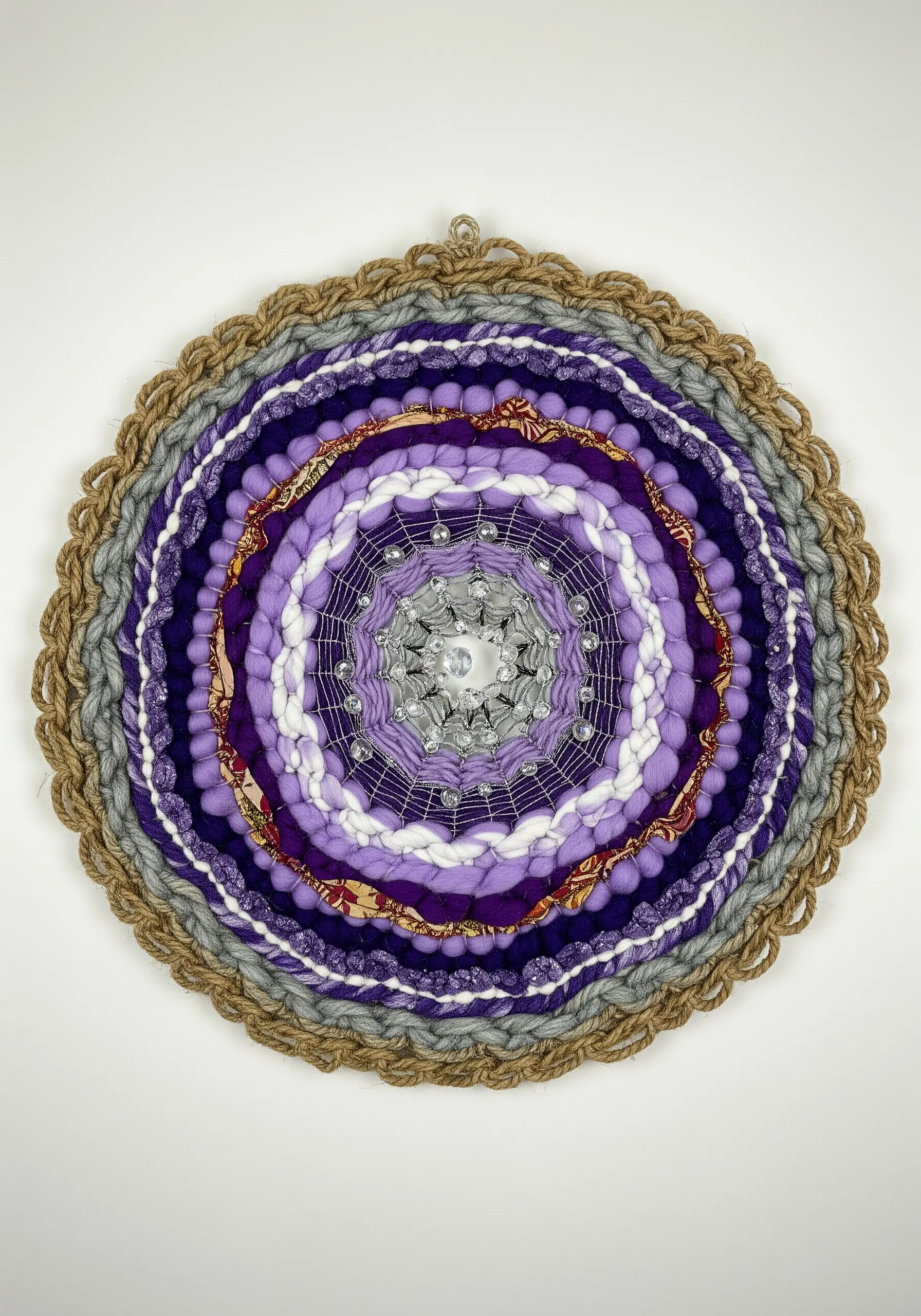 Circular woven wall hanging in purple tones with a beaded center, resembling a mandala.