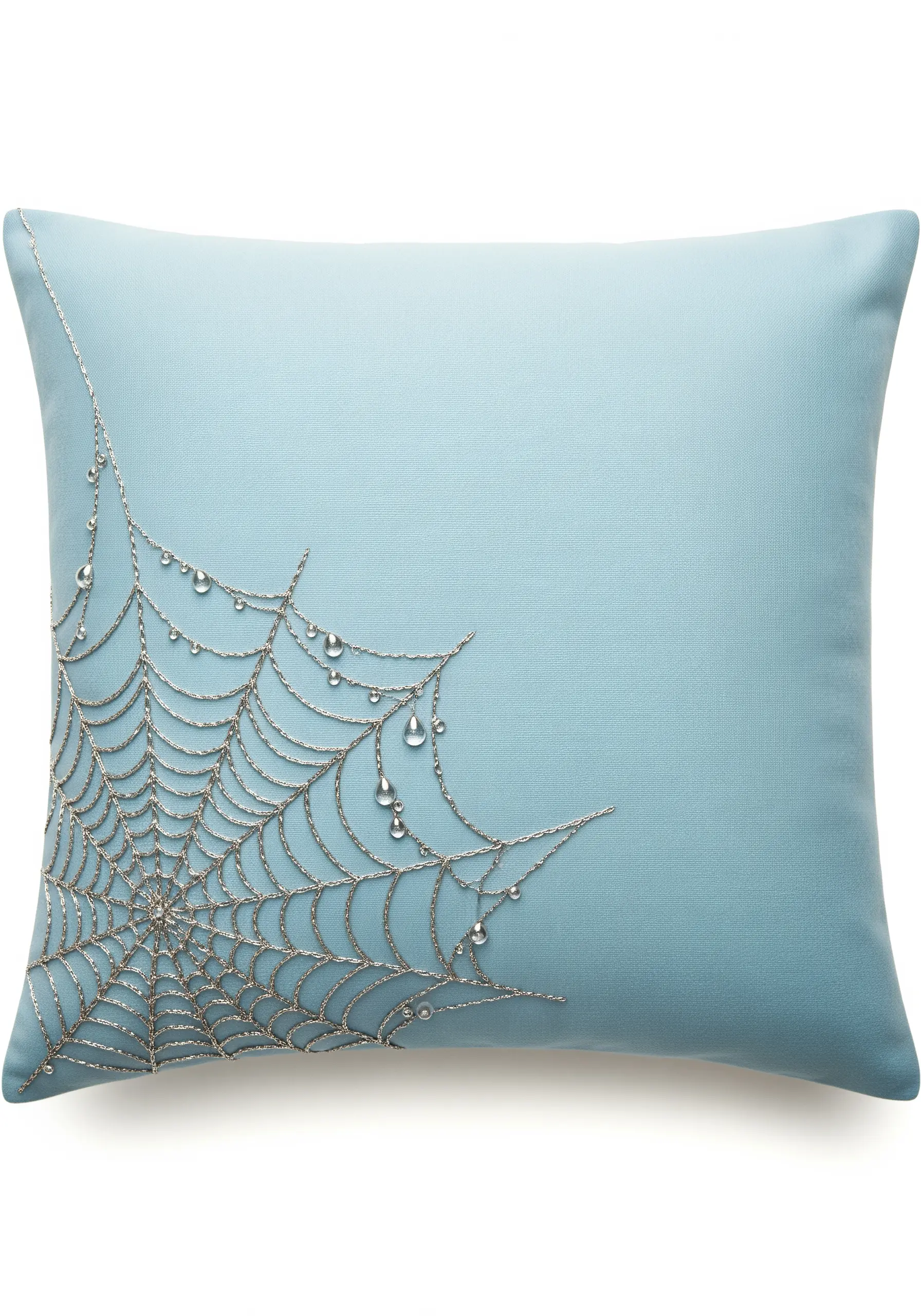 An elegant spiderweb embroidered in the corner of a blue pillow with silver thread and crystal beads.