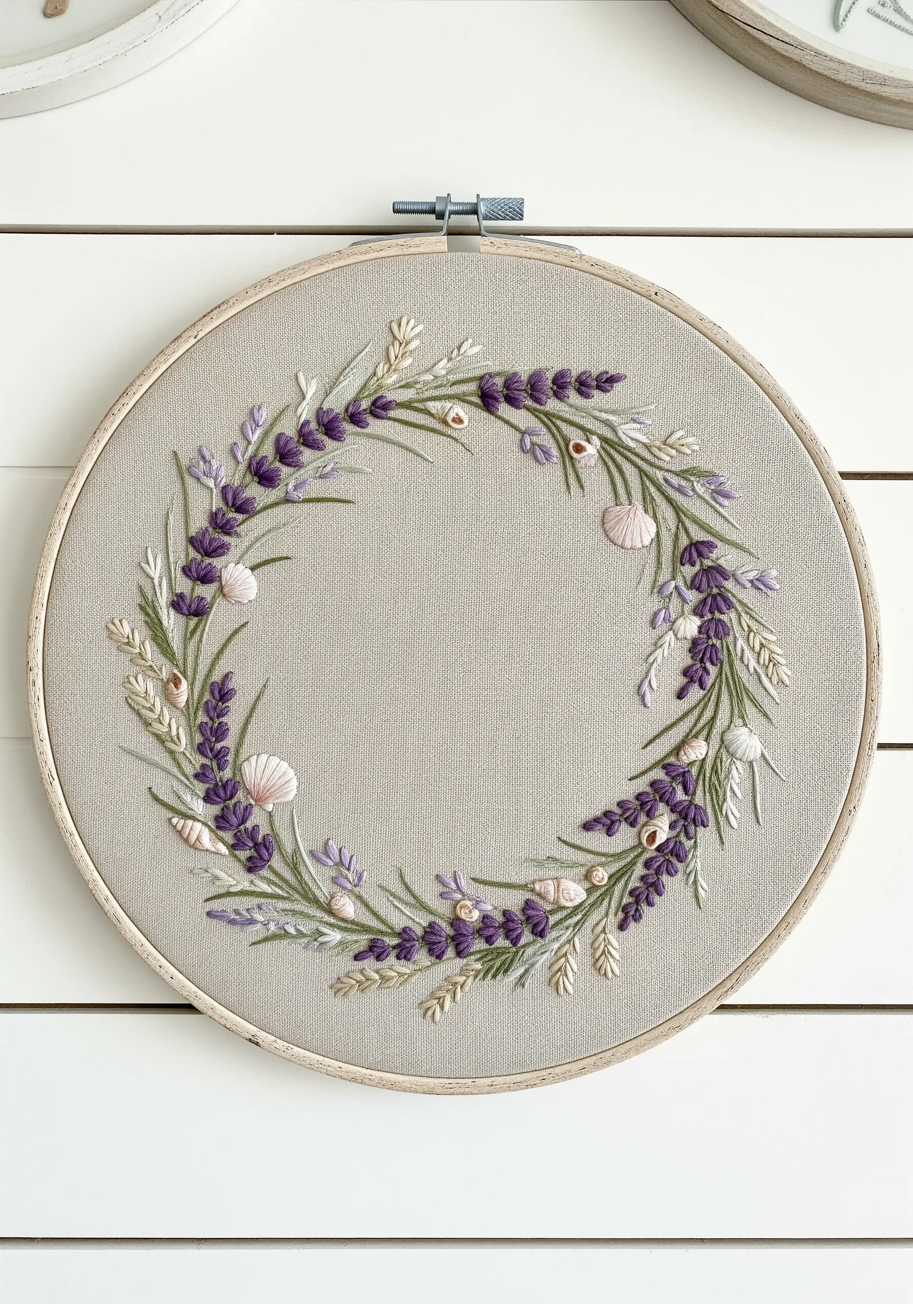 A coastal-themed embroidery wreath with lavender, sea oats, and small stitched seashells.