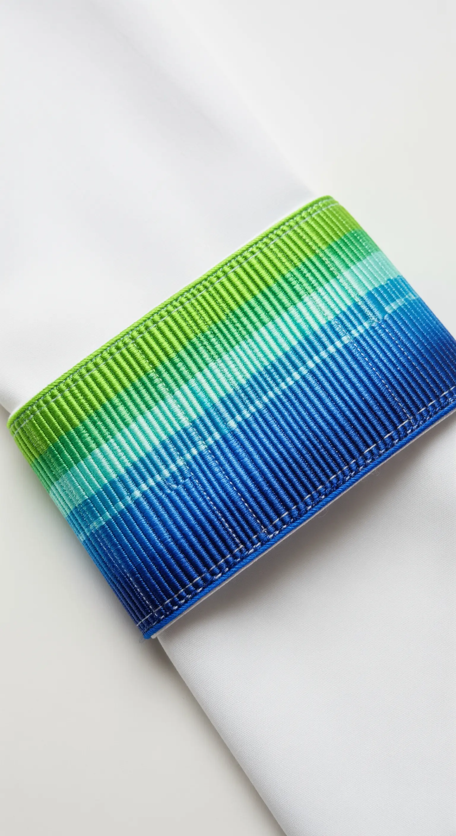 A blue-and-green gradient embroidered napkin ring with a tight, woven texture.