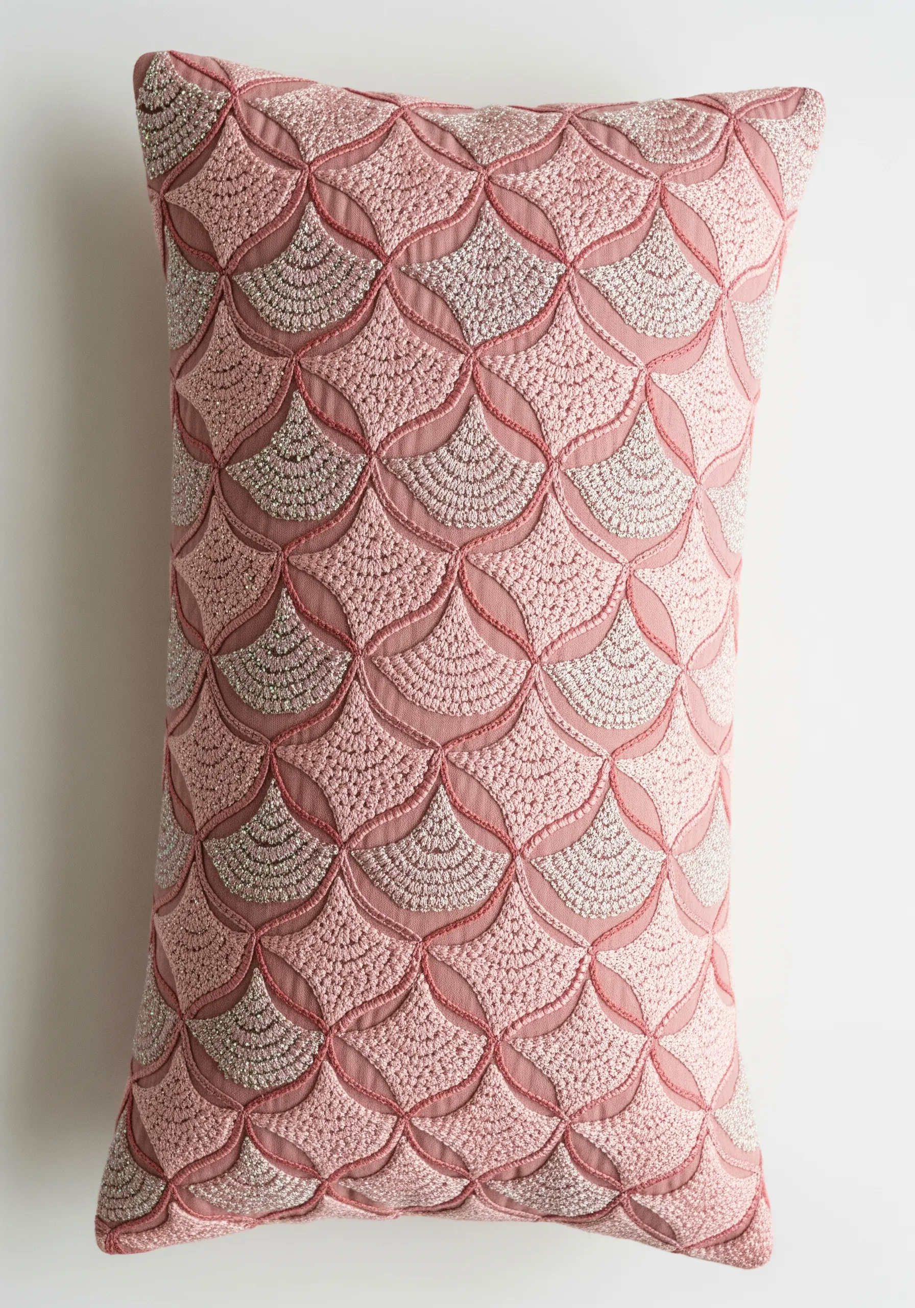 Pillow with a dense, geometric scalloped pattern in pink and silver thread.