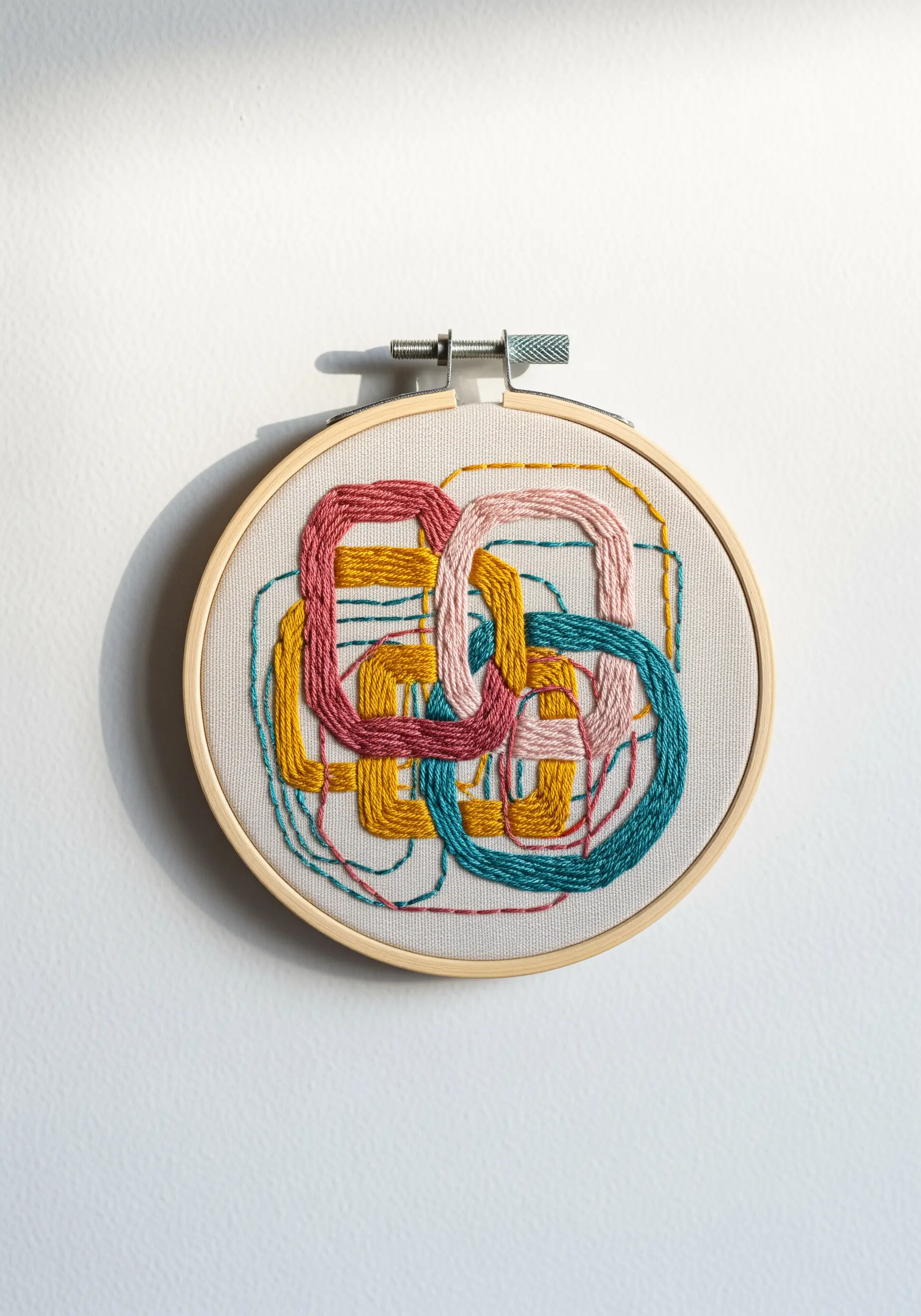 Abstract hoop art with interwoven, colorful satin-stitched chain link shapes.