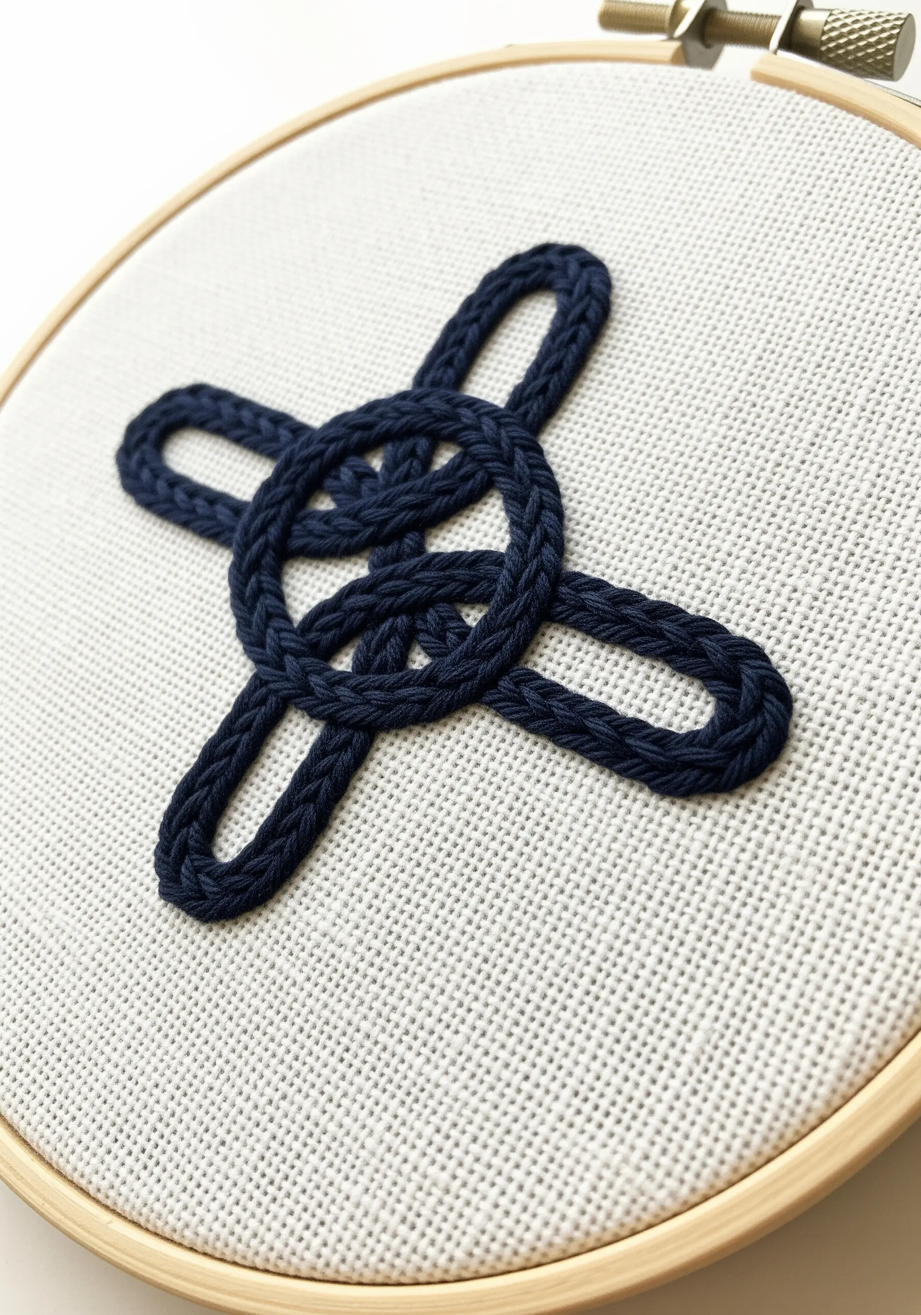 A three-dimensional Celtic knot embroidered with a raised chain stitch band.