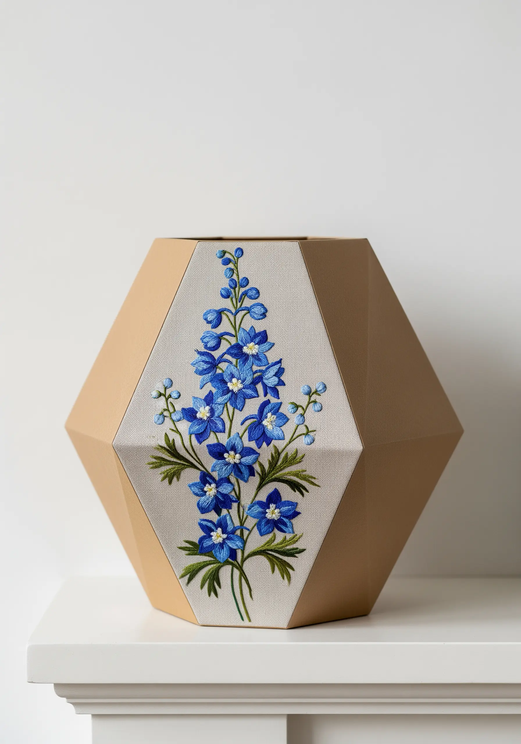 A faceted paper vase featuring a panel of blue delphinium floral embroidery.