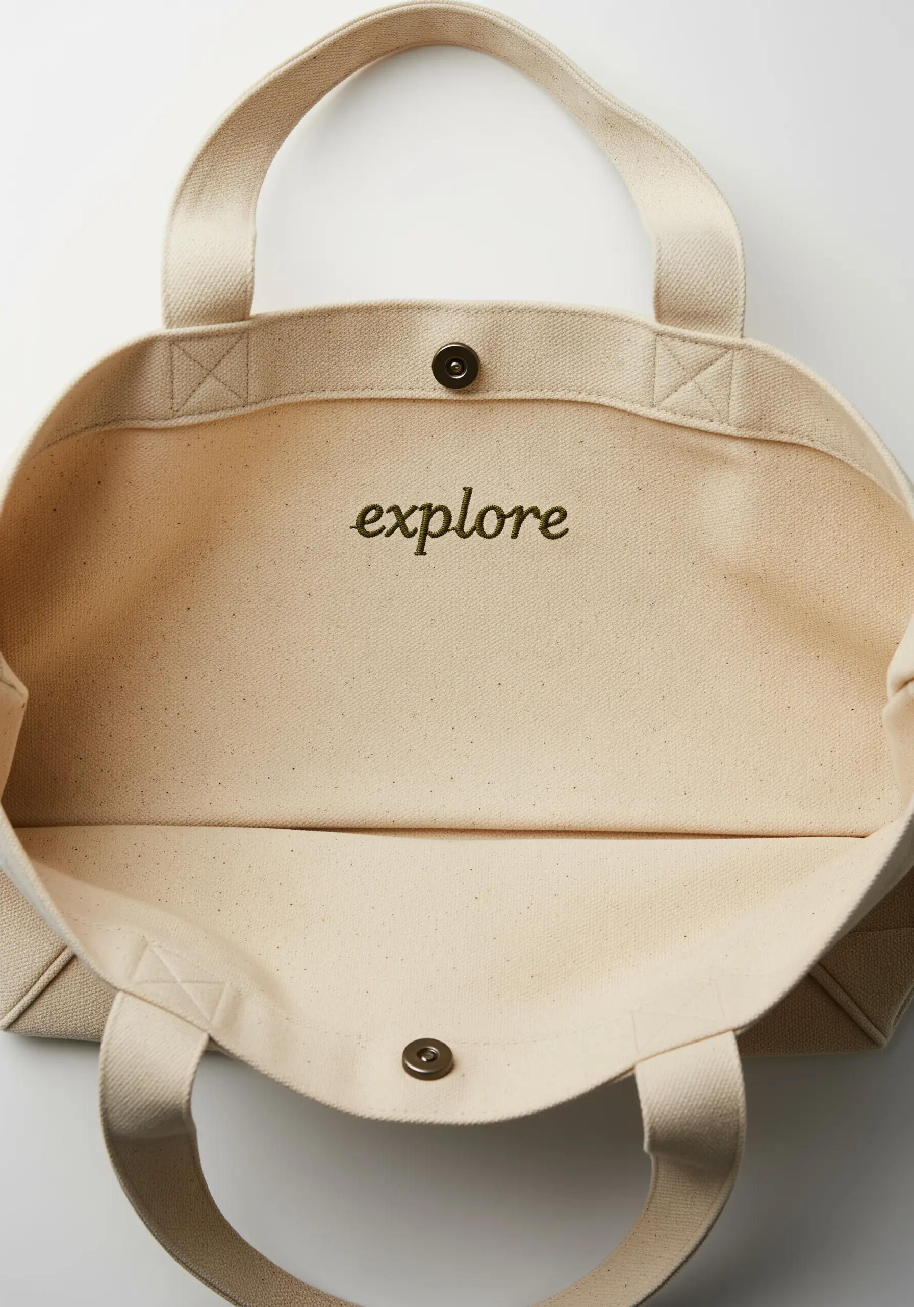 The word 'explore' embroidered in cursive green thread on the inside of a canvas tote bag.