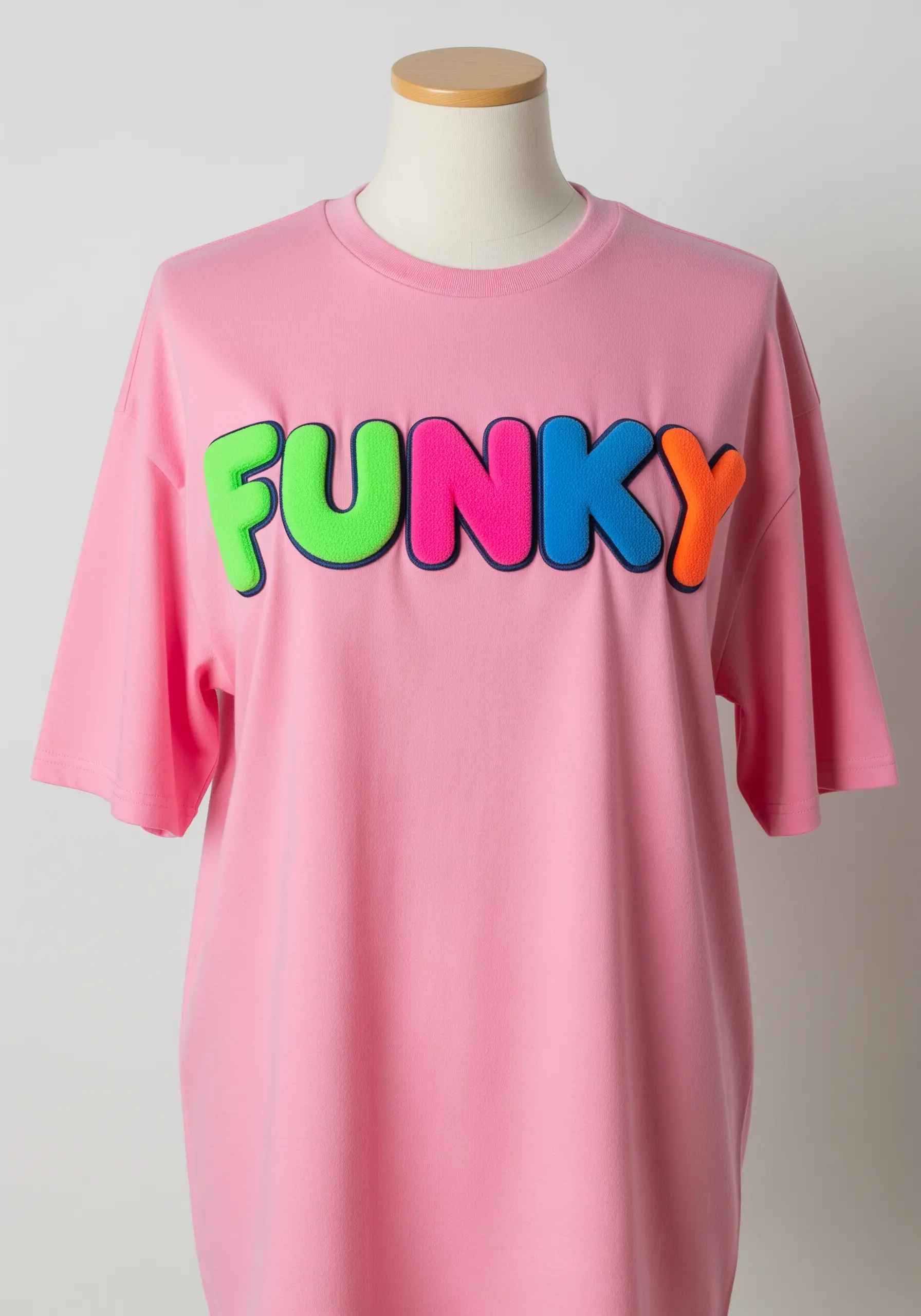 The word 'FUNKY' in colorful, puffy, embroidered bubble letters on a pink t-shirt.