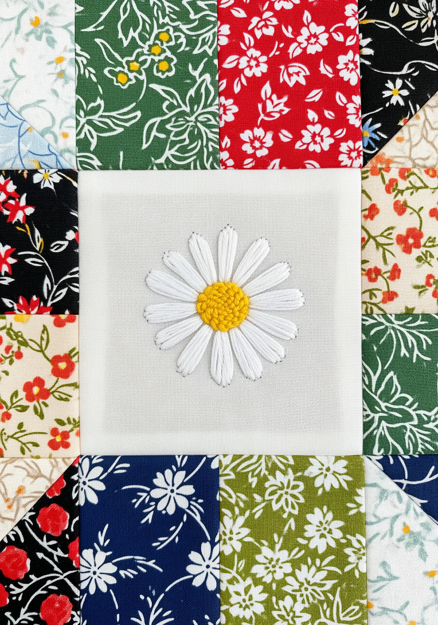 A satin-stitched daisy with a French knot center on a white quilt square.