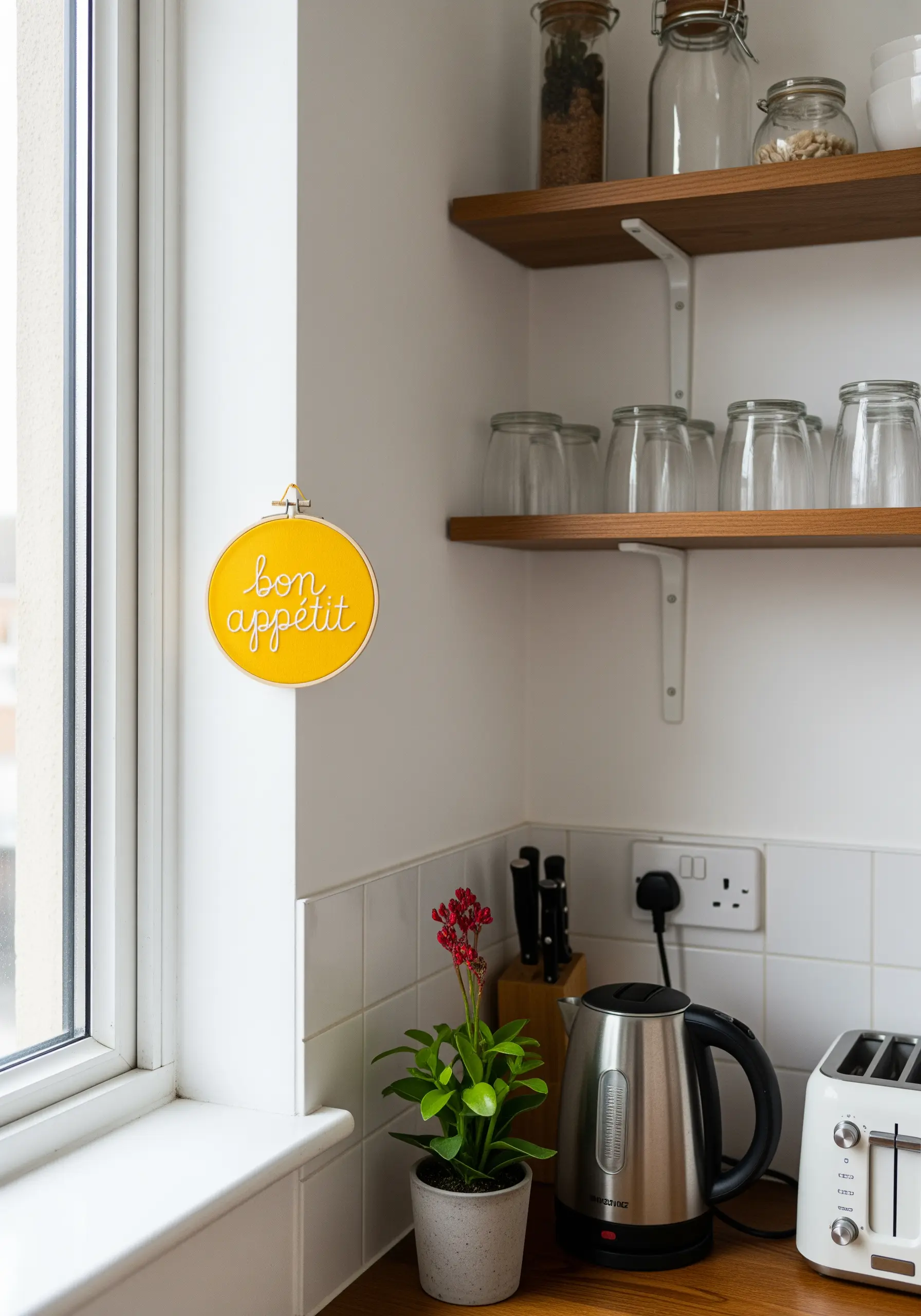 The phrase 'bon appétit' embroidered in white script on a bright yellow fabric in a small hoop.