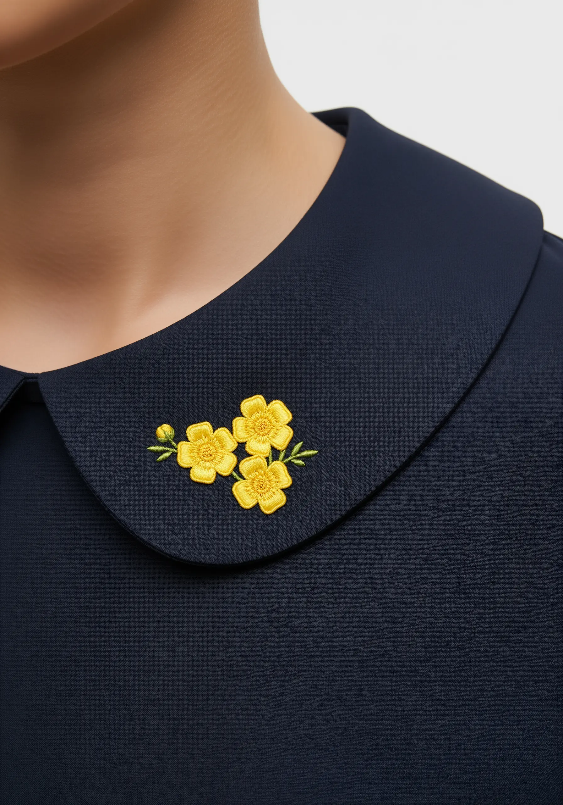 A small cluster of yellow buttercup flowers embroidered on a navy blue shirt collar.