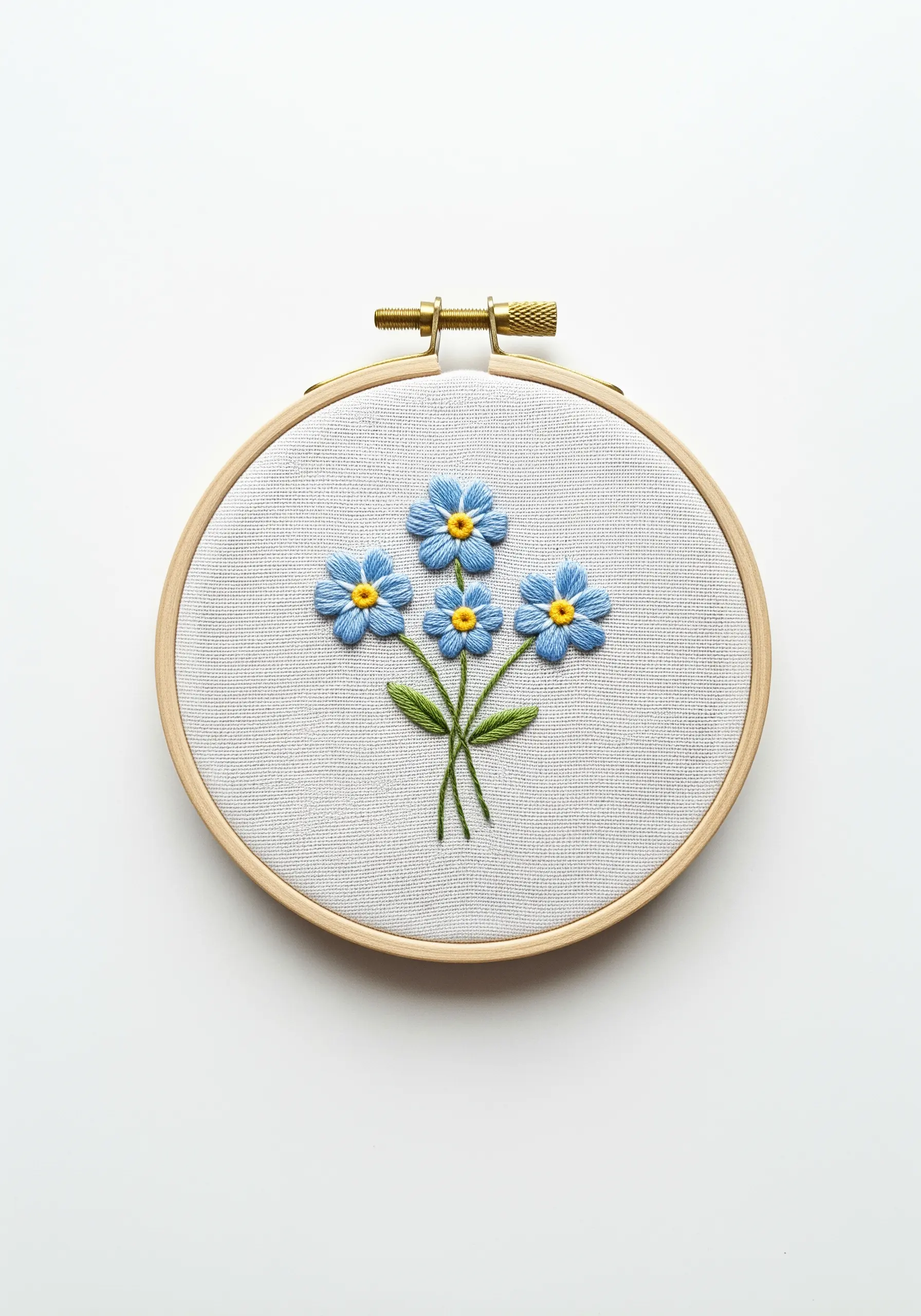 A small bouquet of blue forget-me-not flowers with yellow centers in an embroidery hoop.