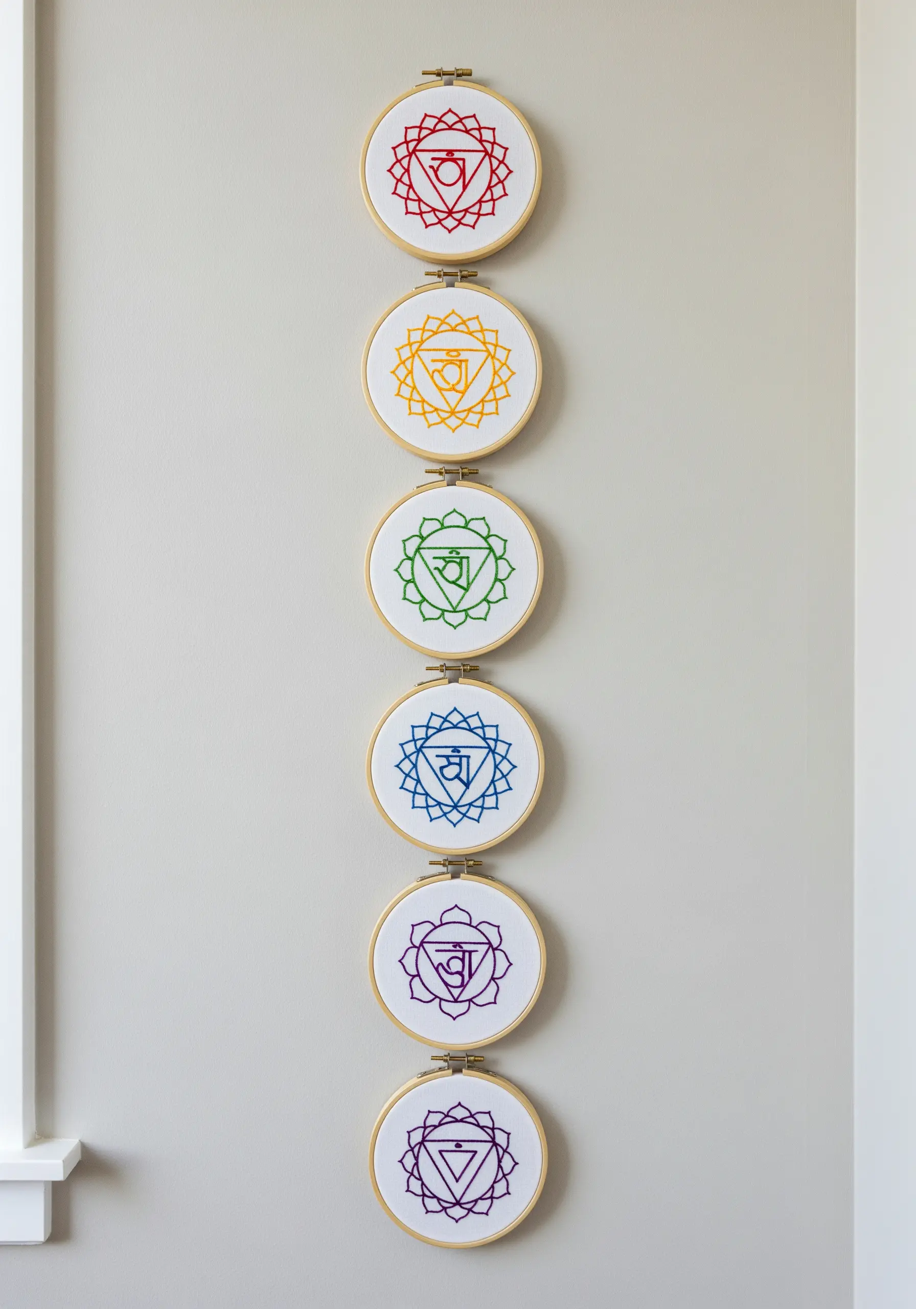 A vertical column of seven embroidery hoops, each displaying a different colored chakra symbol.