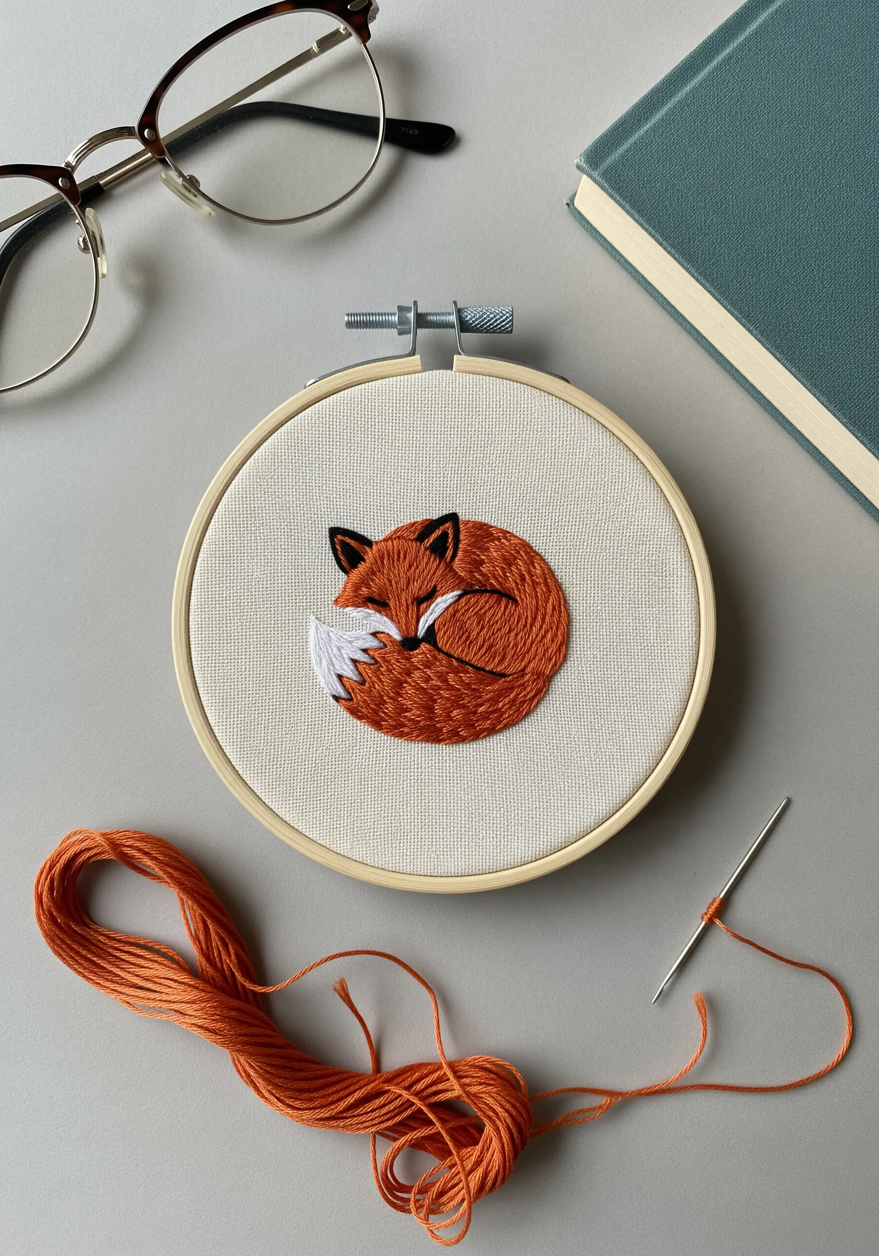 A sleeping fox embroidered with blended orange threads to create a soft fur texture.