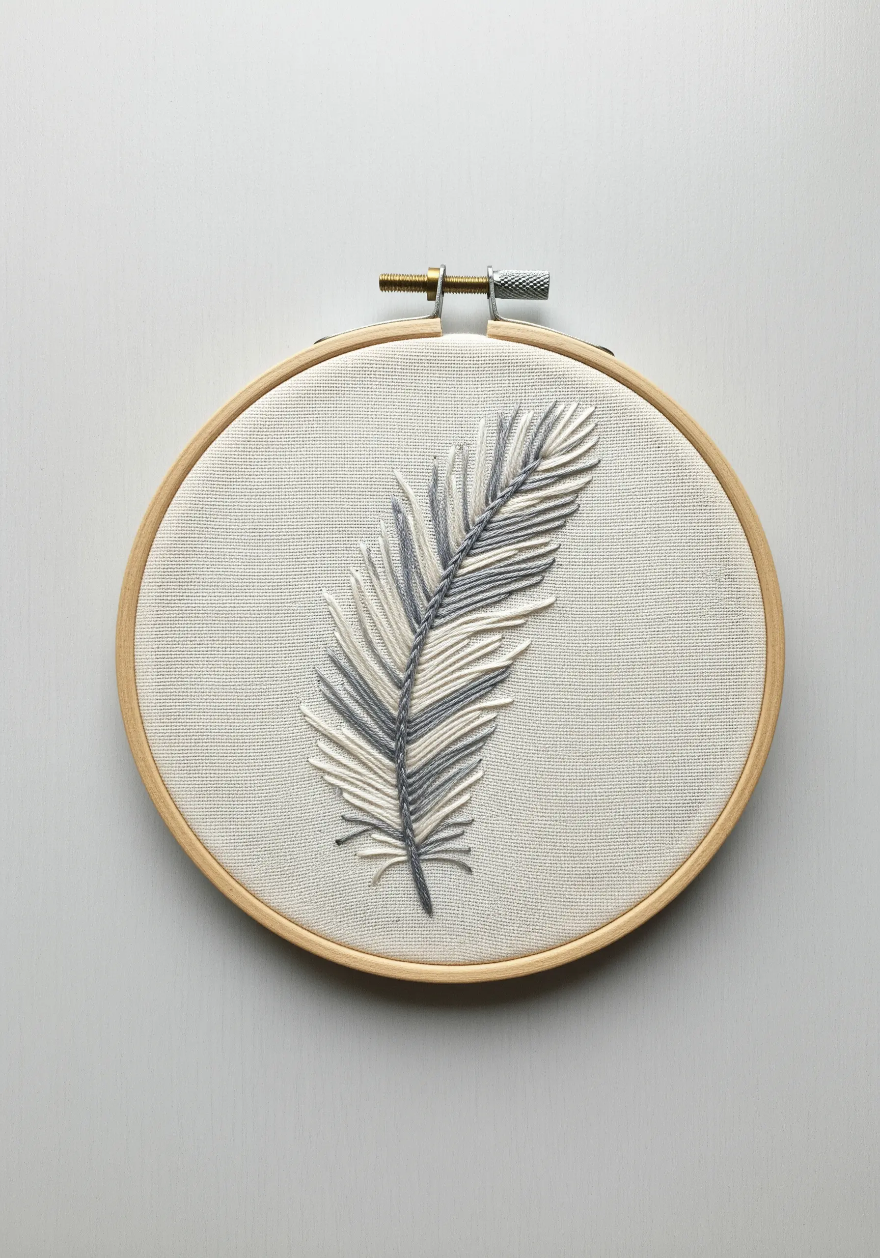 A feather stitched in grey and off-white using the fishbone stitch.