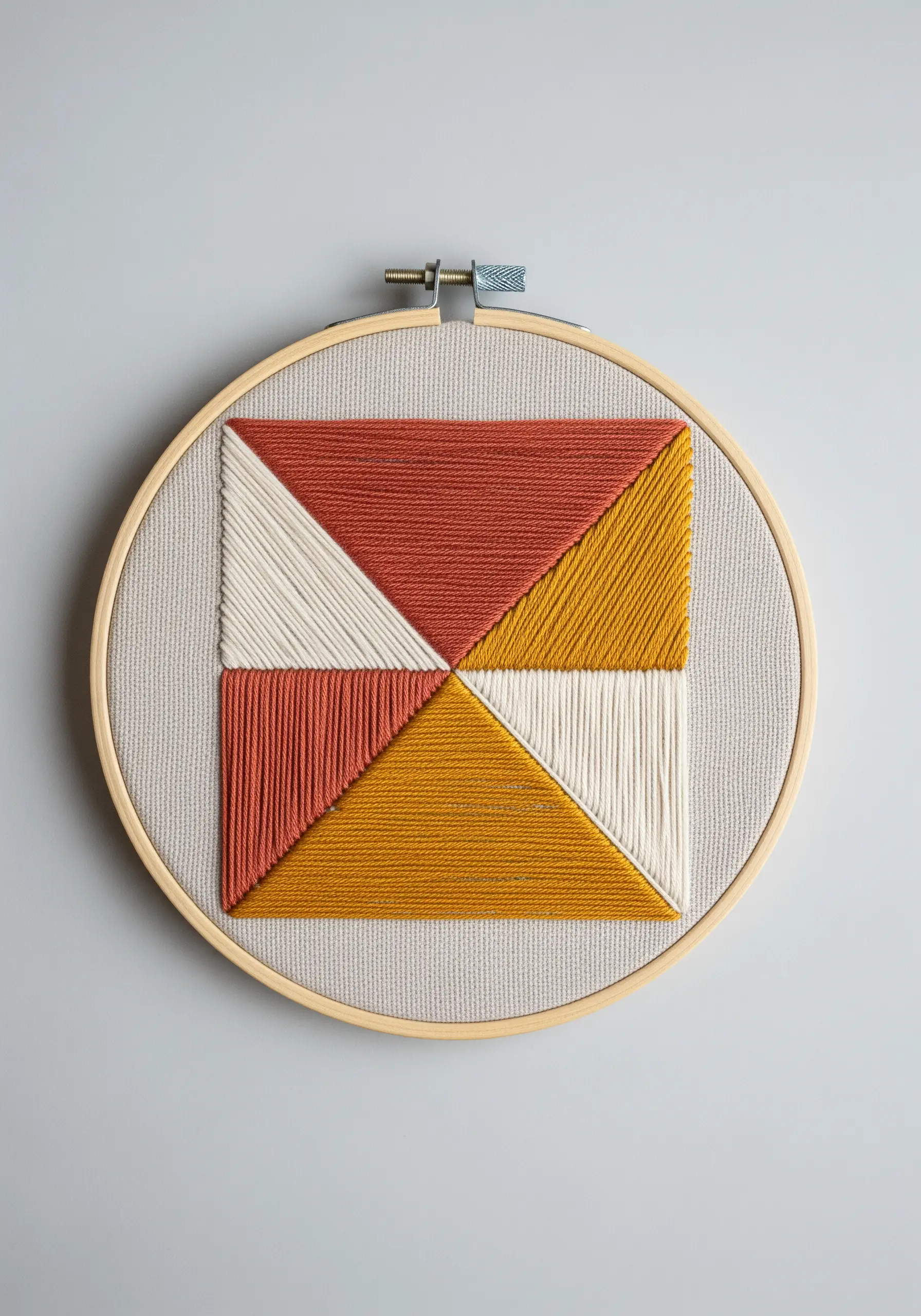 A geometric pattern of four triangles filled with satin stitch in warm tones.