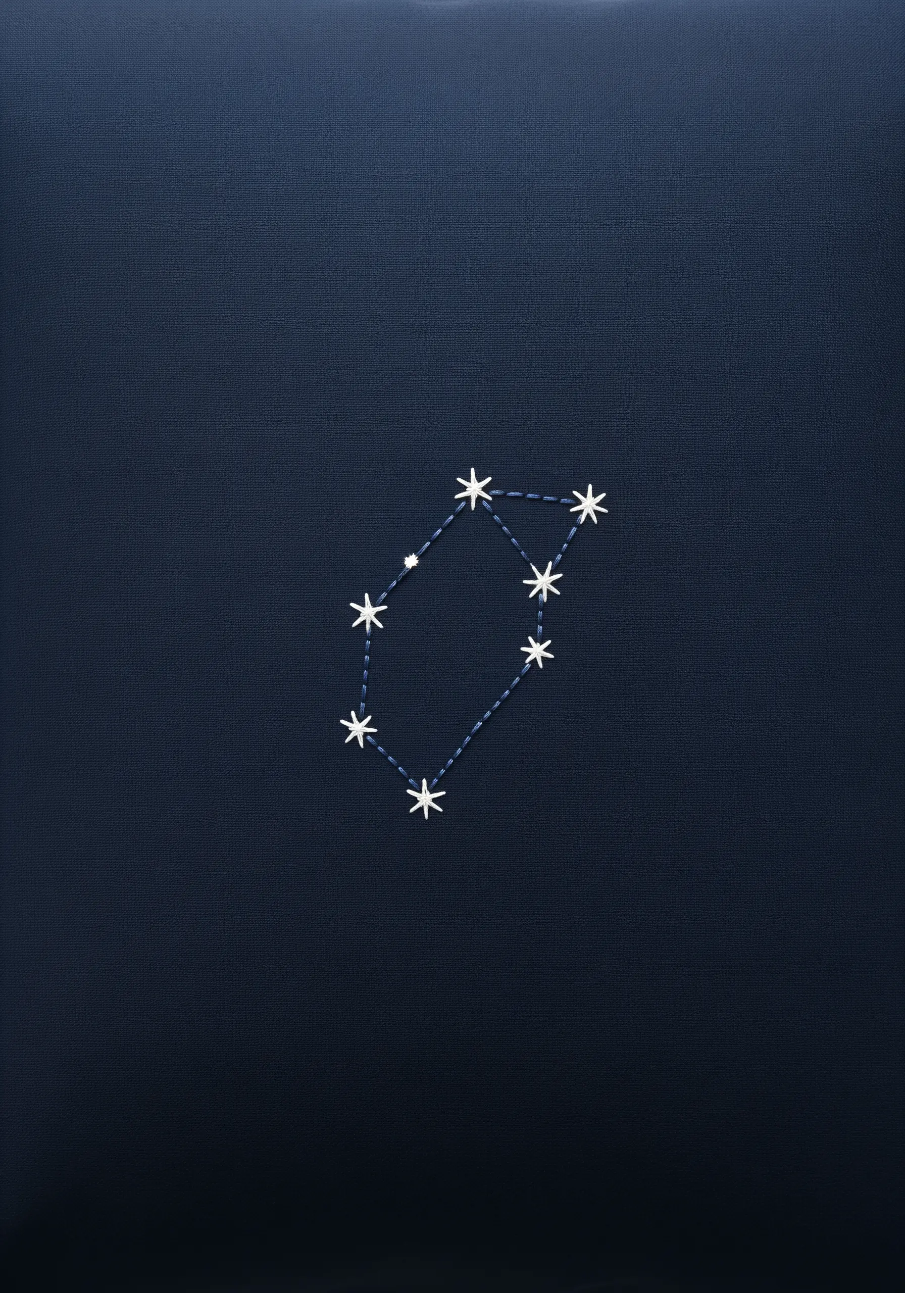 A simple star constellation embroidered with white thread on a dark navy blue pillowcase.