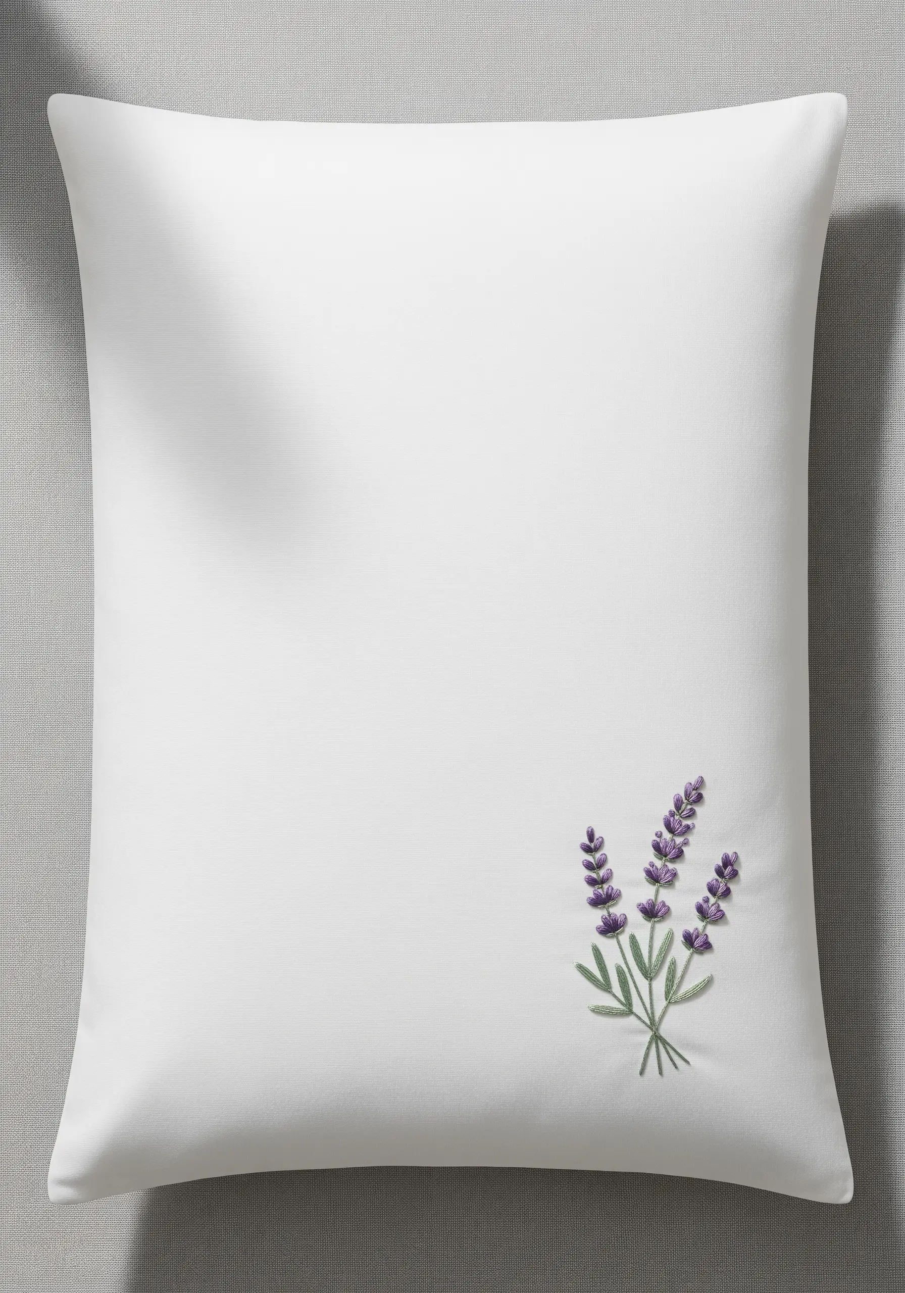 A small sprig of lavender embroidered in the bottom right corner of a white pillowcase.