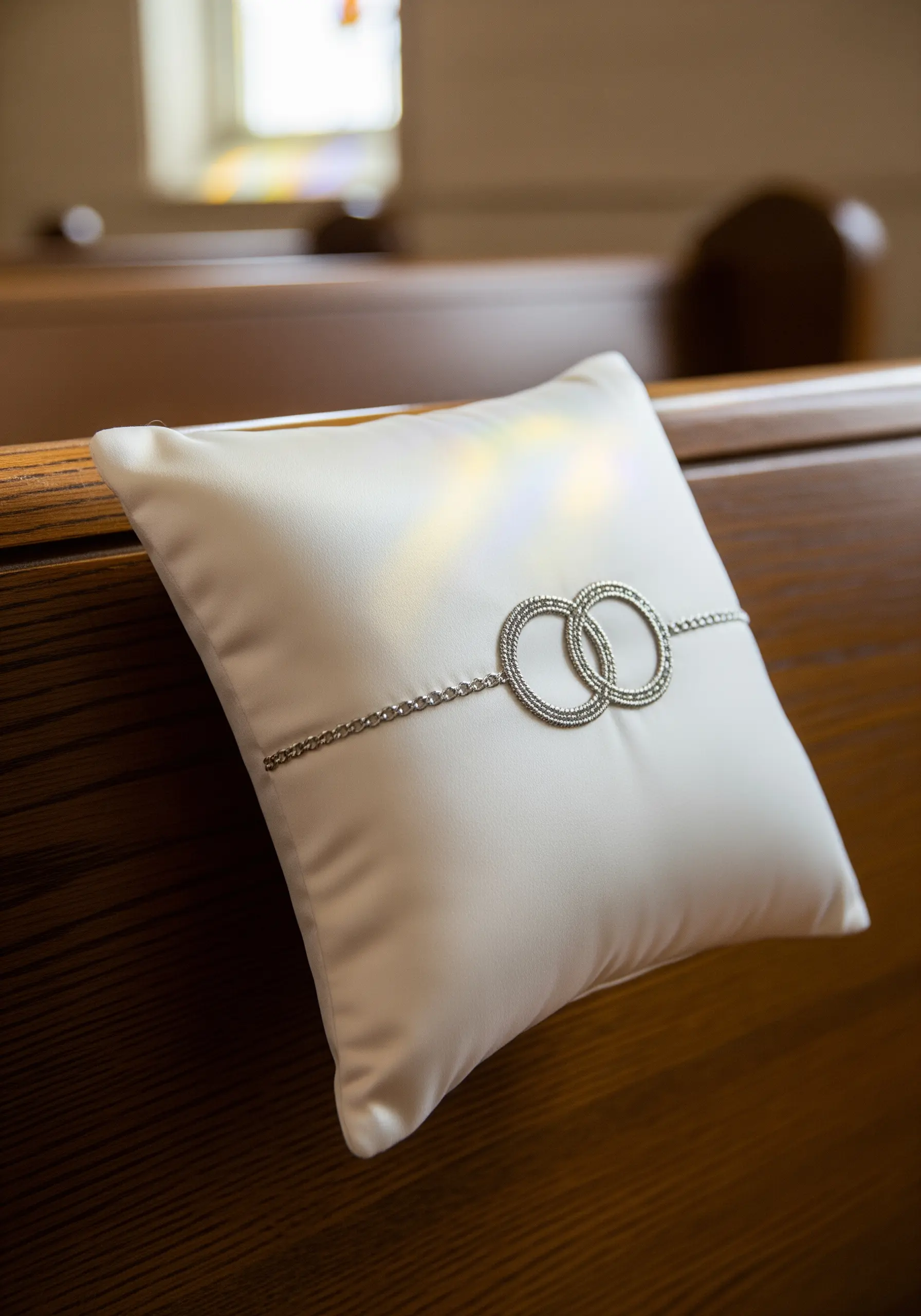 Satin ring bearer pillow with two interlocking rings made from beads.