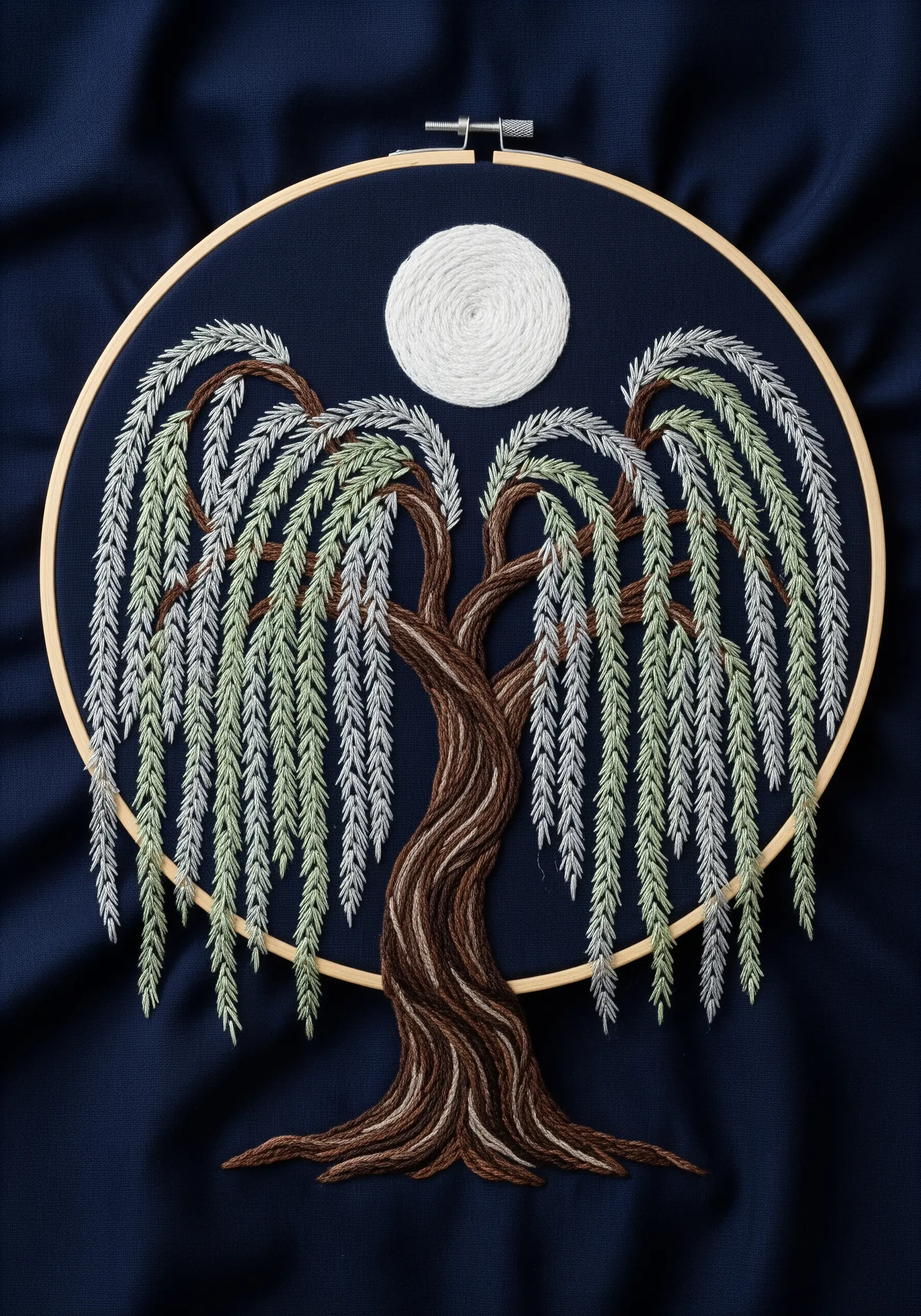 An embroidered weeping willow tree under a full moon, with long, flowing silver and green branches.