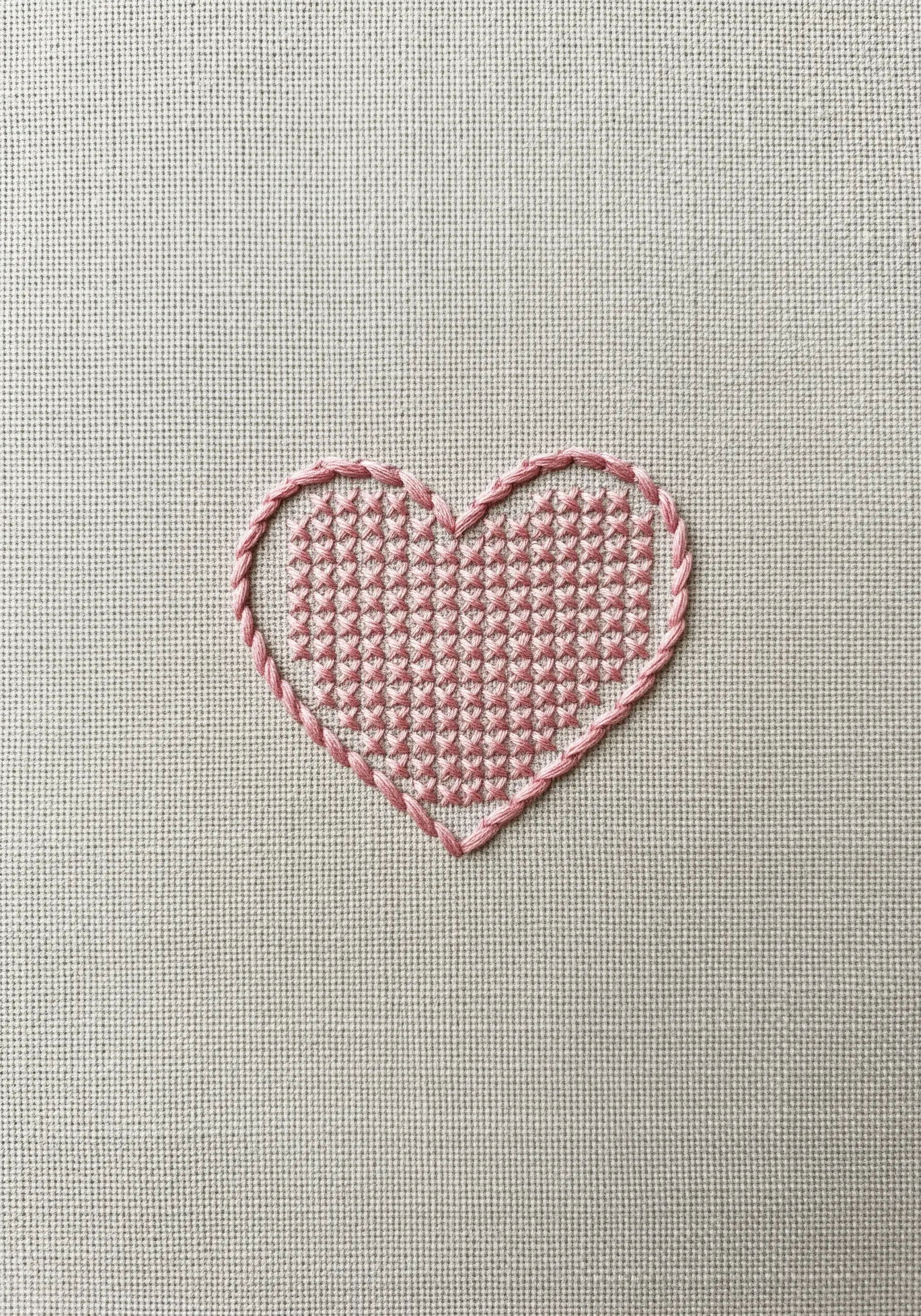 A heart shape outlined in pink and filled with a geometric cross-stitch pattern.
