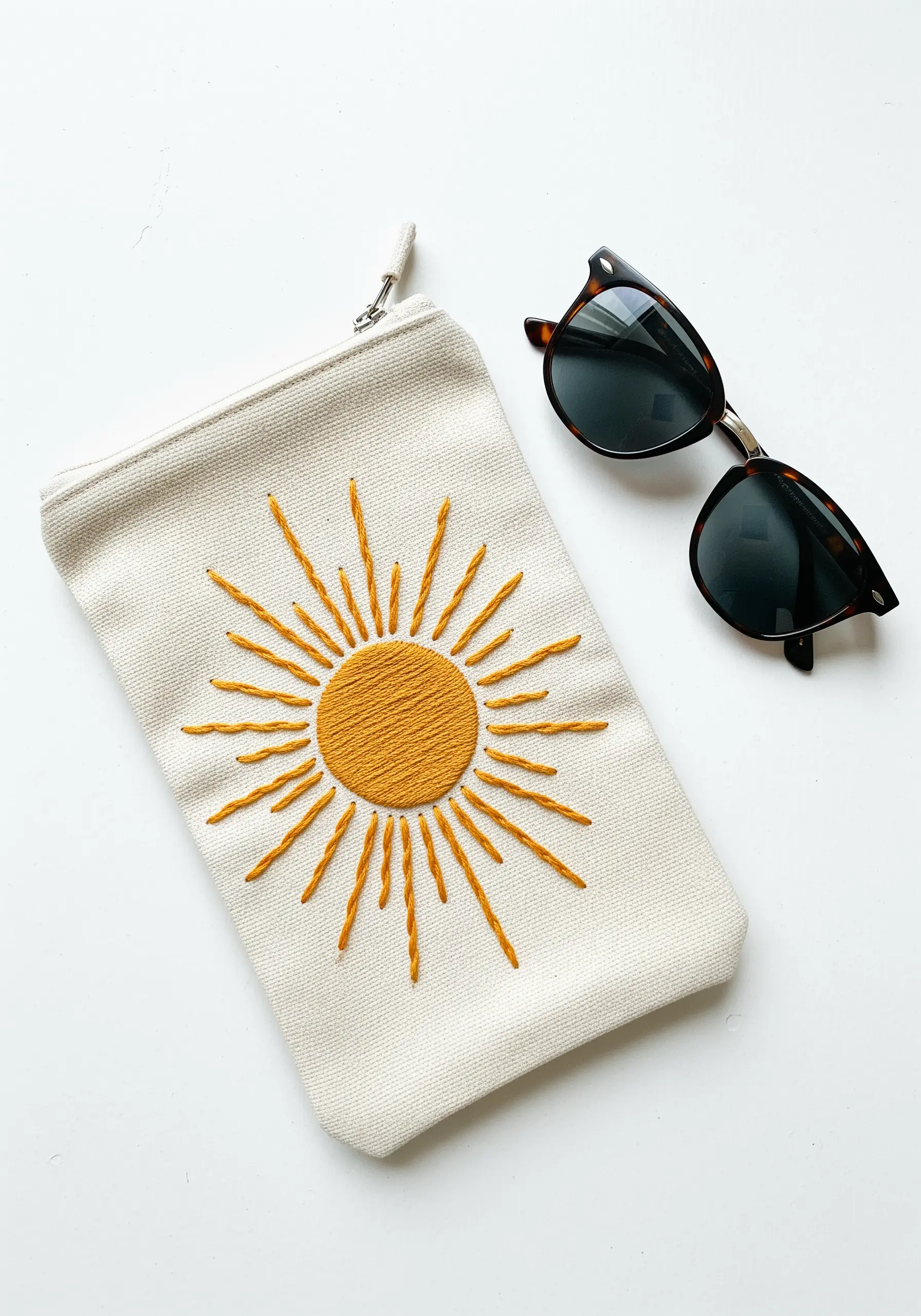 A bright yellow sun with a filled center and radiating lines on a canvas pouch.