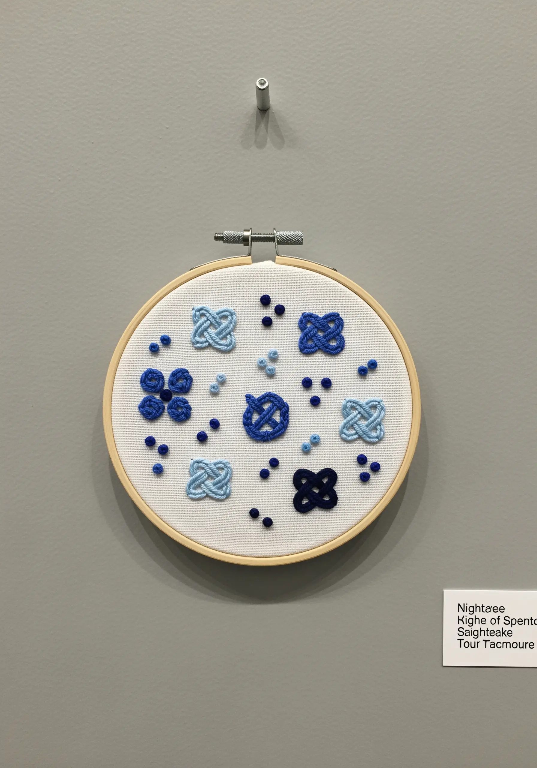 A sampler hoop featuring various decorative knots in shades of blue.