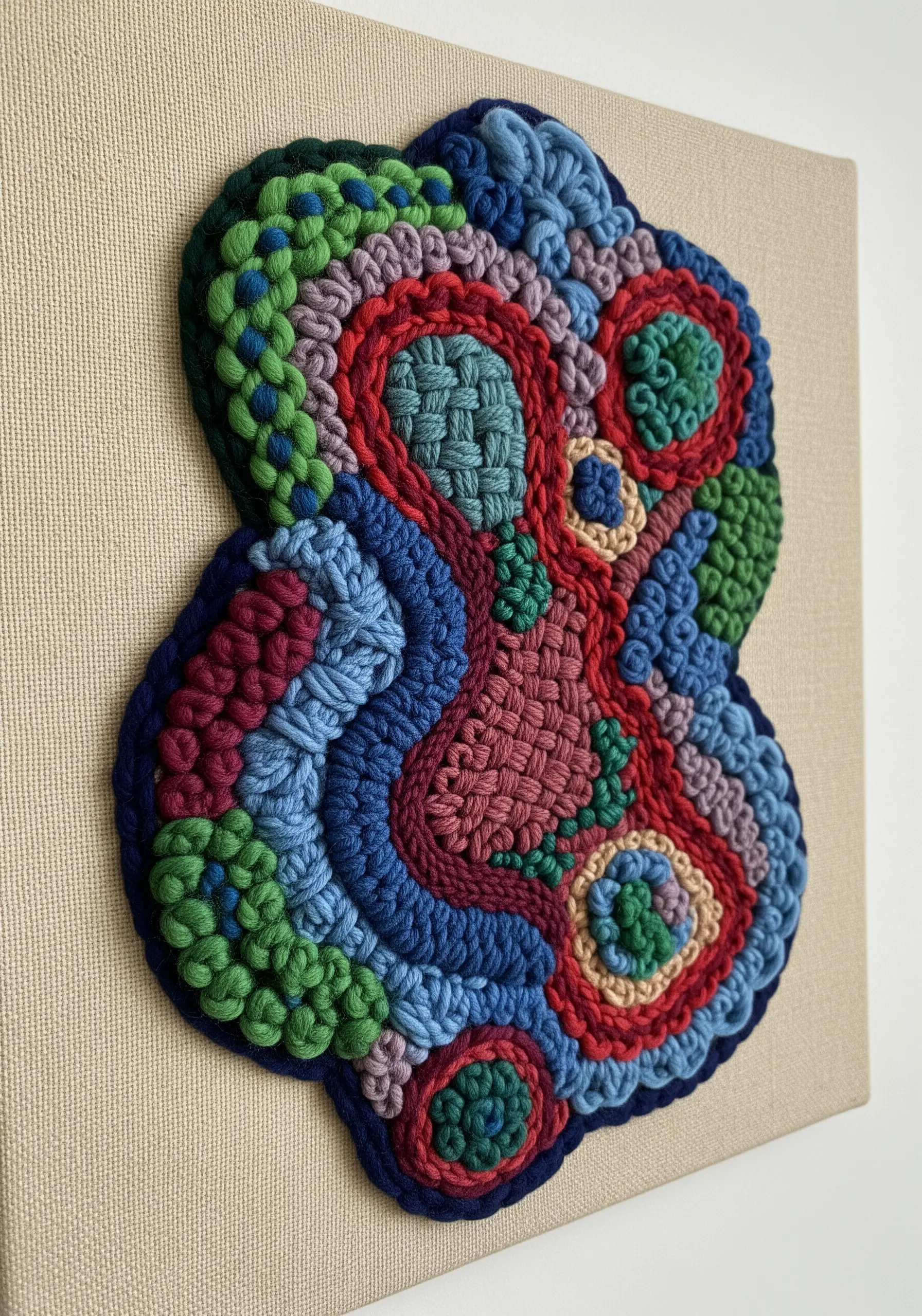 A colorful, biomorphic shape filled with a variety of highly textured embroidery stitches.