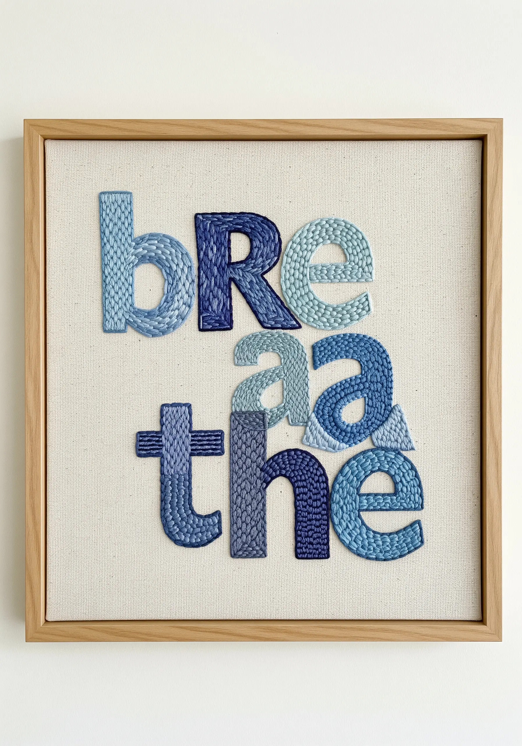 The word 'breathe' embroidered with different blue textured stitches for each letter.