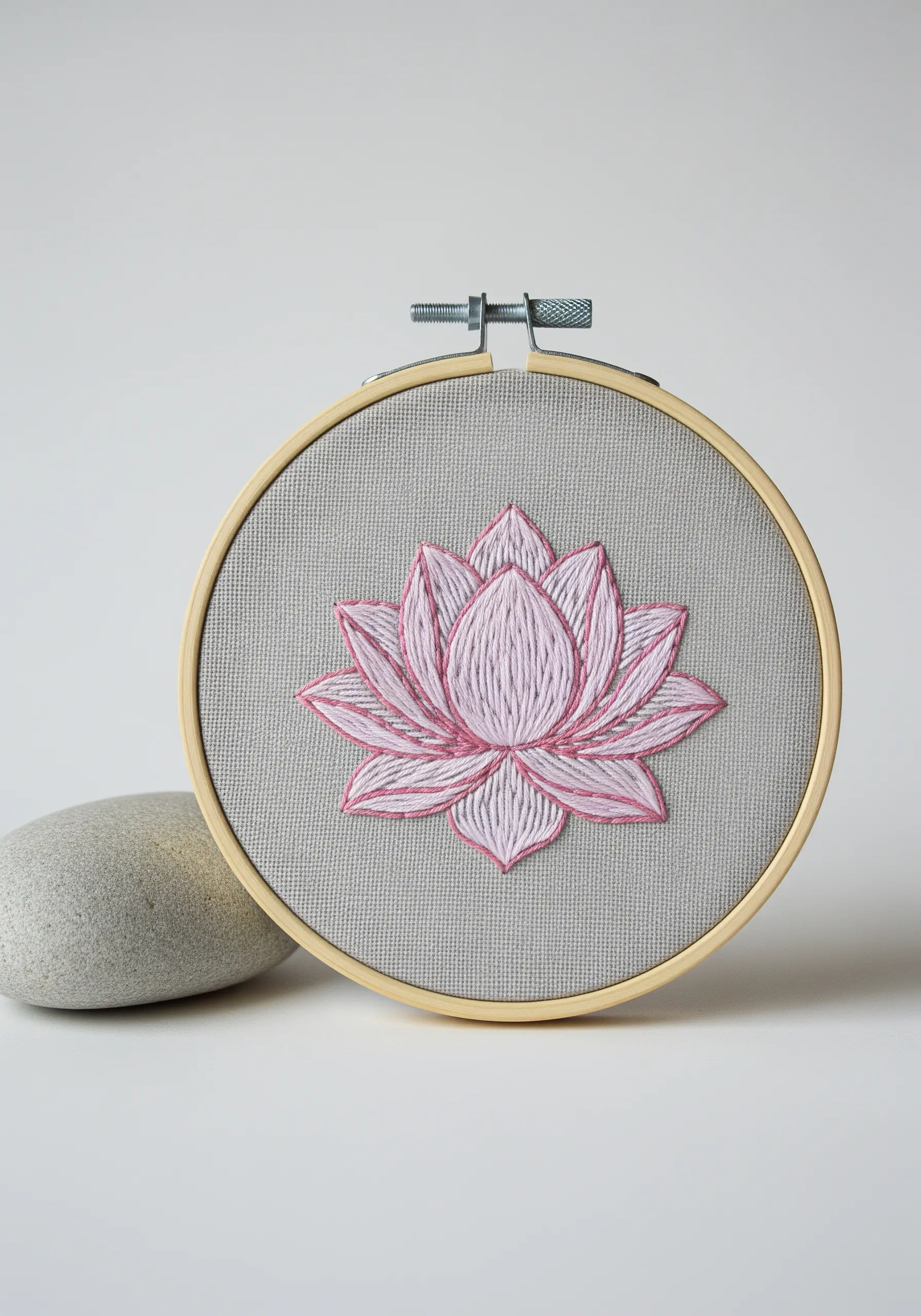An embroidered pink lotus flower with a darker pink outline on grey fabric.