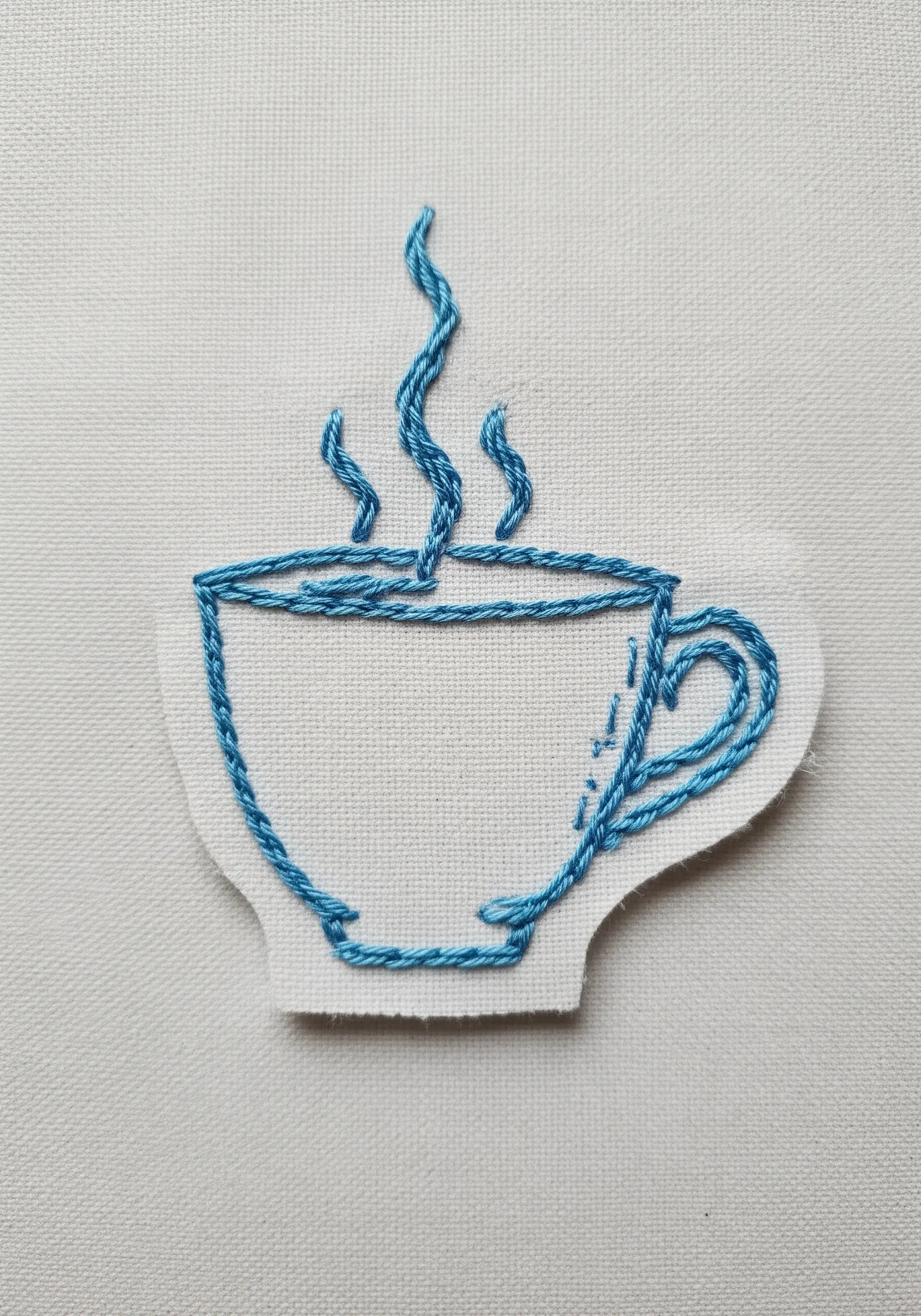 An embroidered patch of a coffee cup outline with wavy steam rising from it.