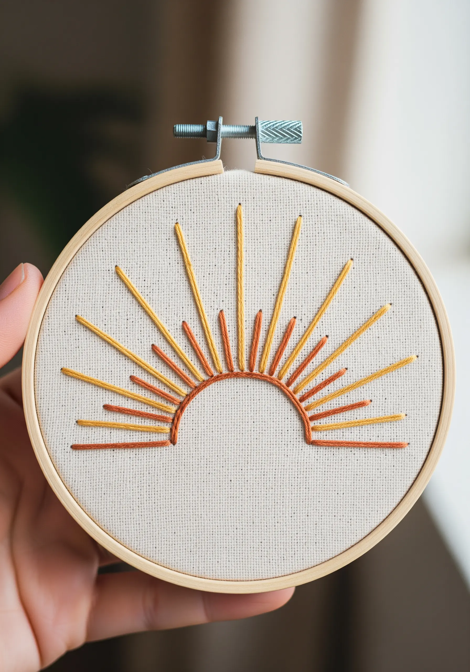 Minimalist embroidered sunburst with orange and yellow radiating stitches.