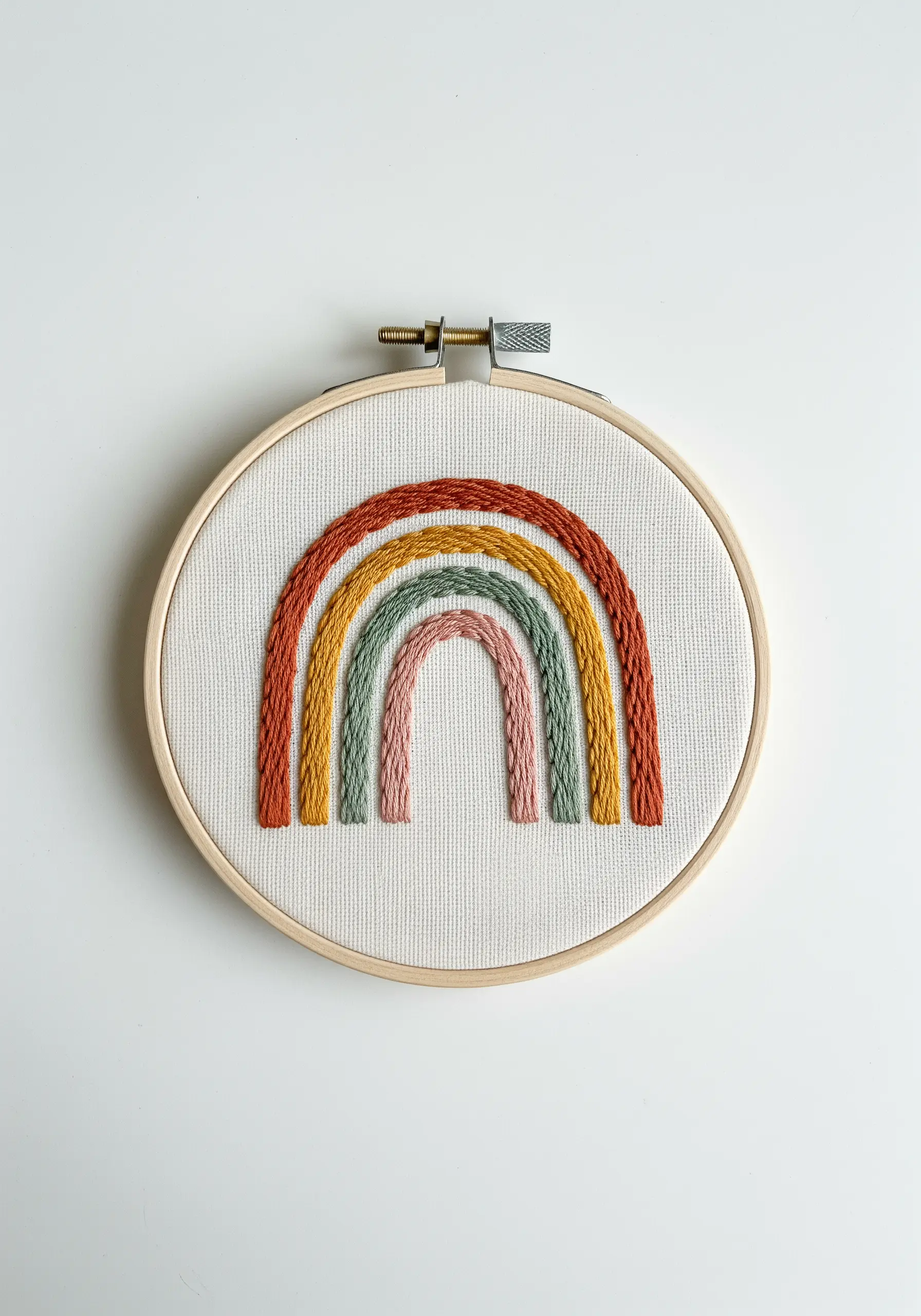 A boho rainbow embroidered with thick, textured chain stitches in earthy tones.