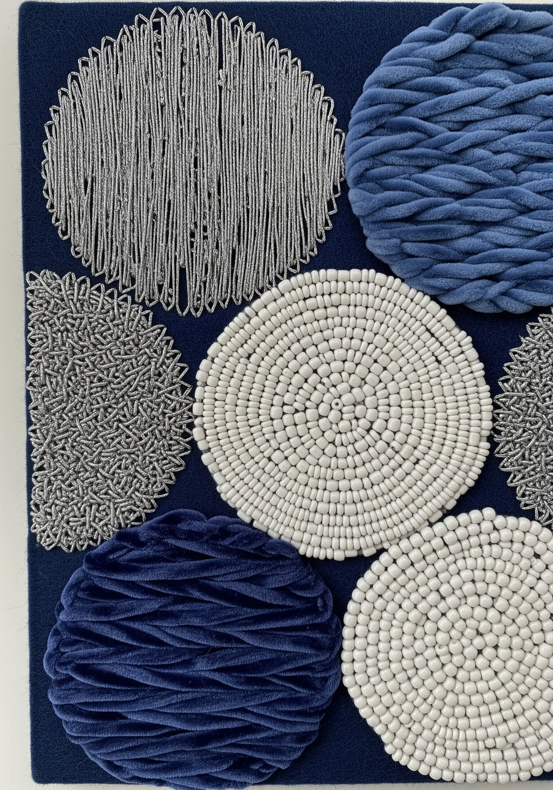 Abstract circles filled with blue velvet yarn, white beads, and silver metallic thread.