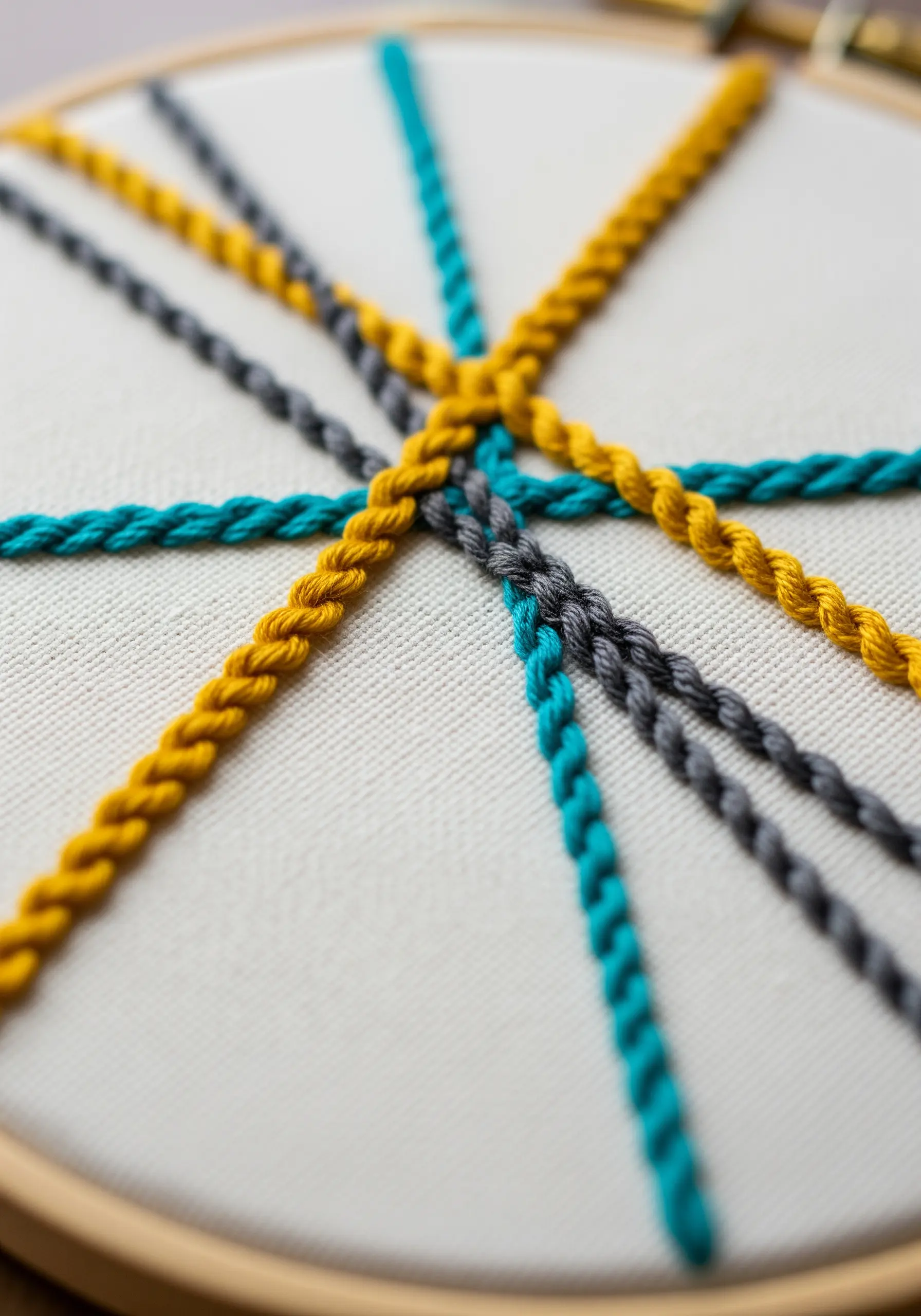 Intersecting lines of yellow, teal, and grey chain stitch, woven together.