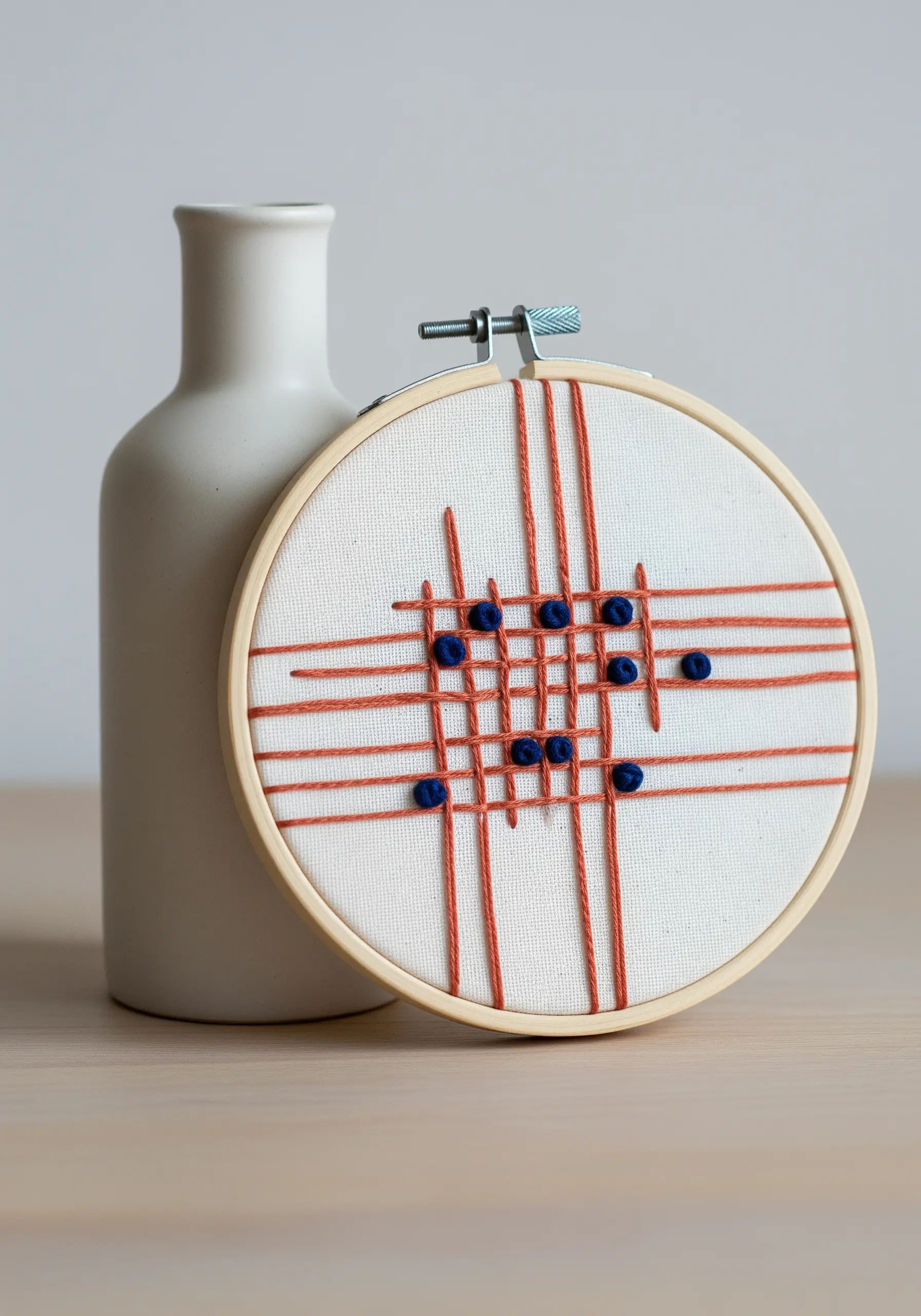 An abstract geometric design with orange lines and blue knots on white fabric.