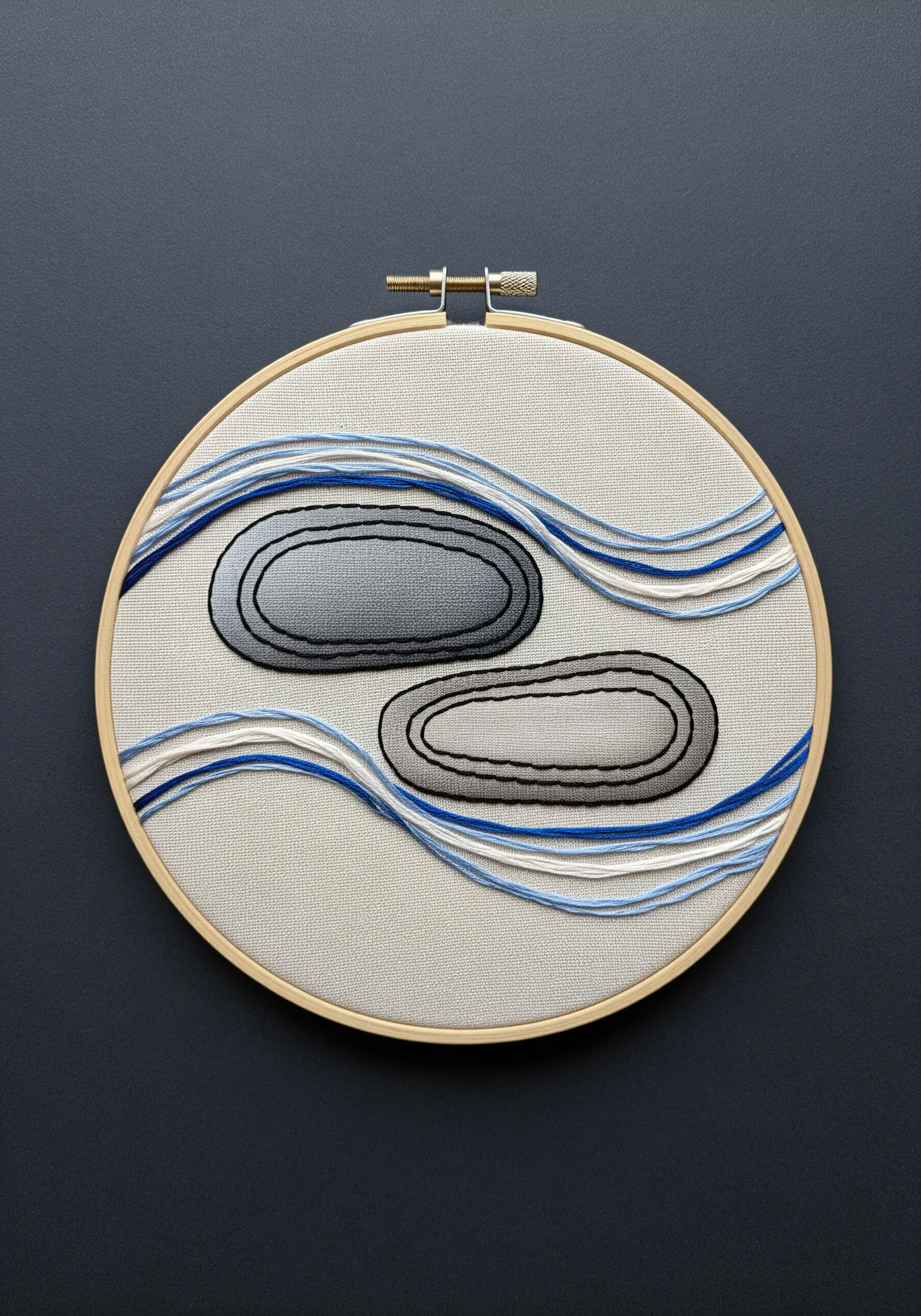 Minimalist embroidery of two stones with flowing blue and white lines on neutral fabric.