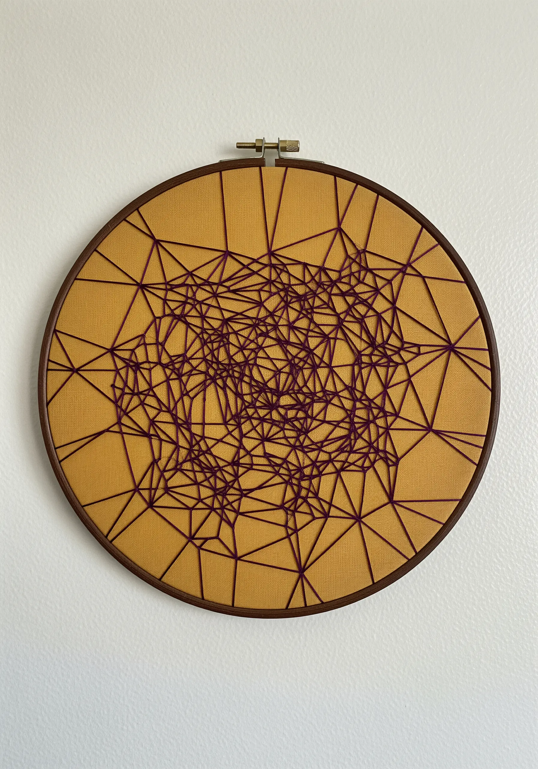 An intricate network of straight purple stitches creating a web-like pattern on mustard-yellow fabric.
