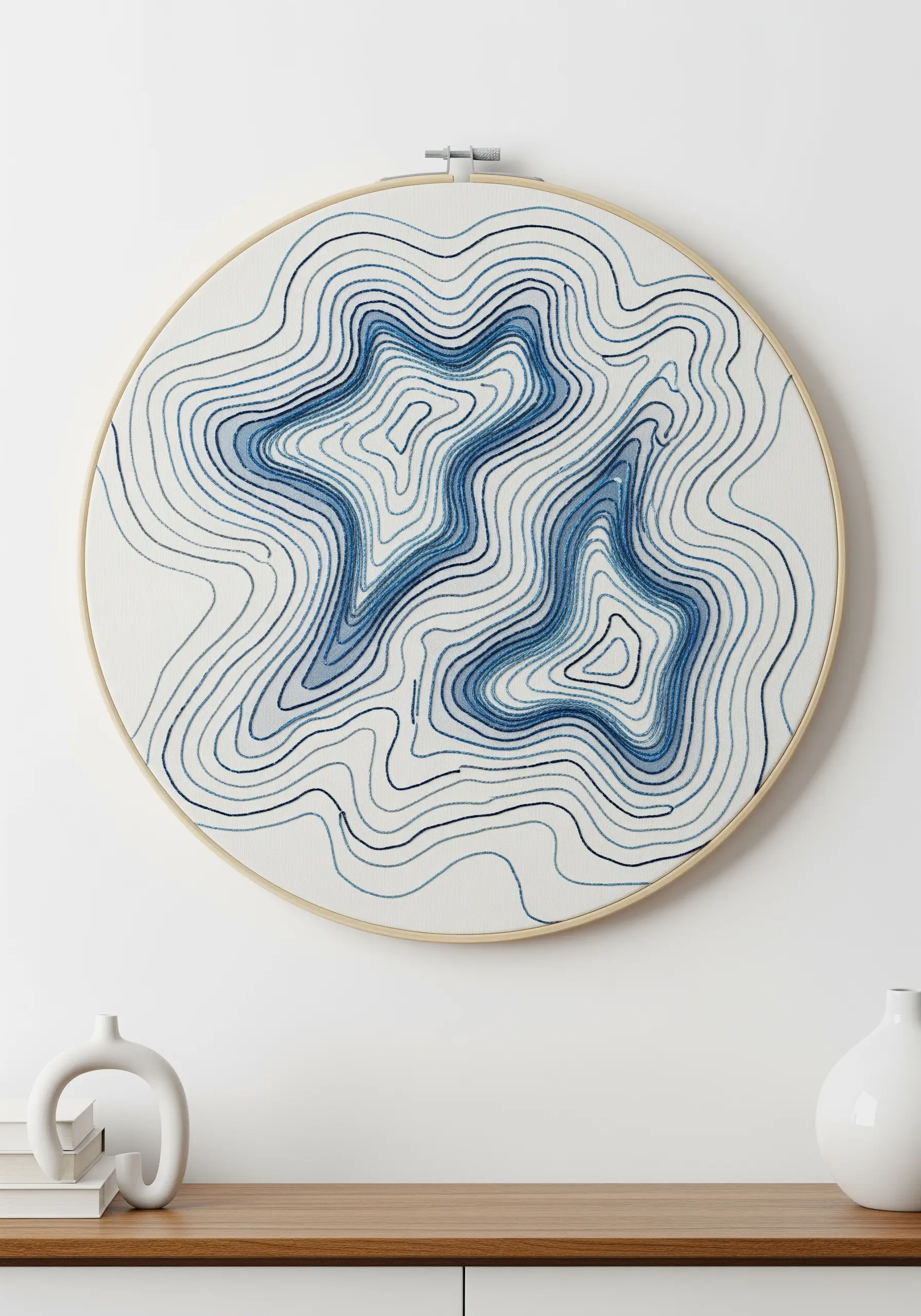 Abstract topographic map of water embroidered with blue backstitch on white fabric.