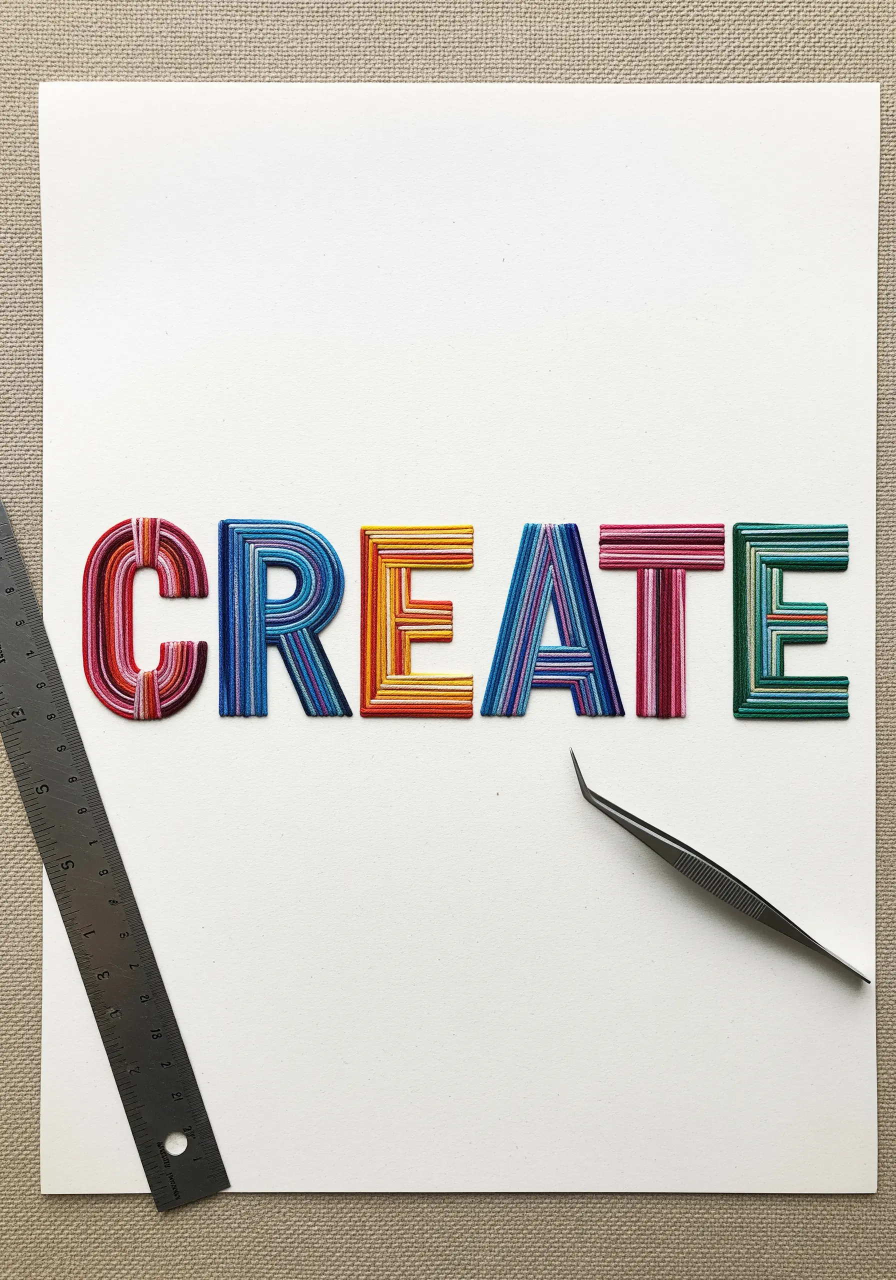 The word 'CREATE' made from colorful, layered paper strips giving it a 3D effect.