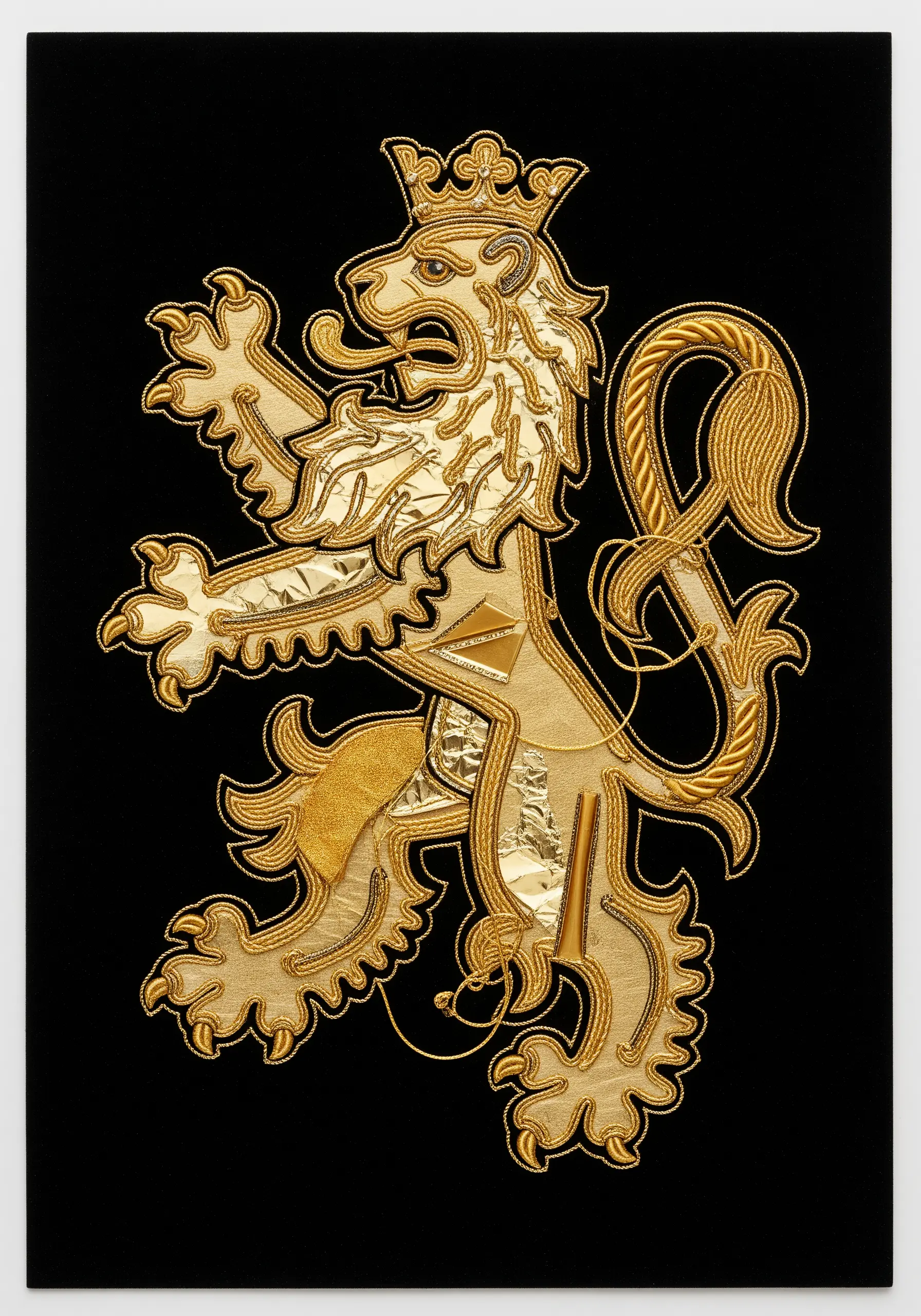 A heraldic lion rendered in gold cords, shiny fabric, and foil on a black background, mimicking goldwork.