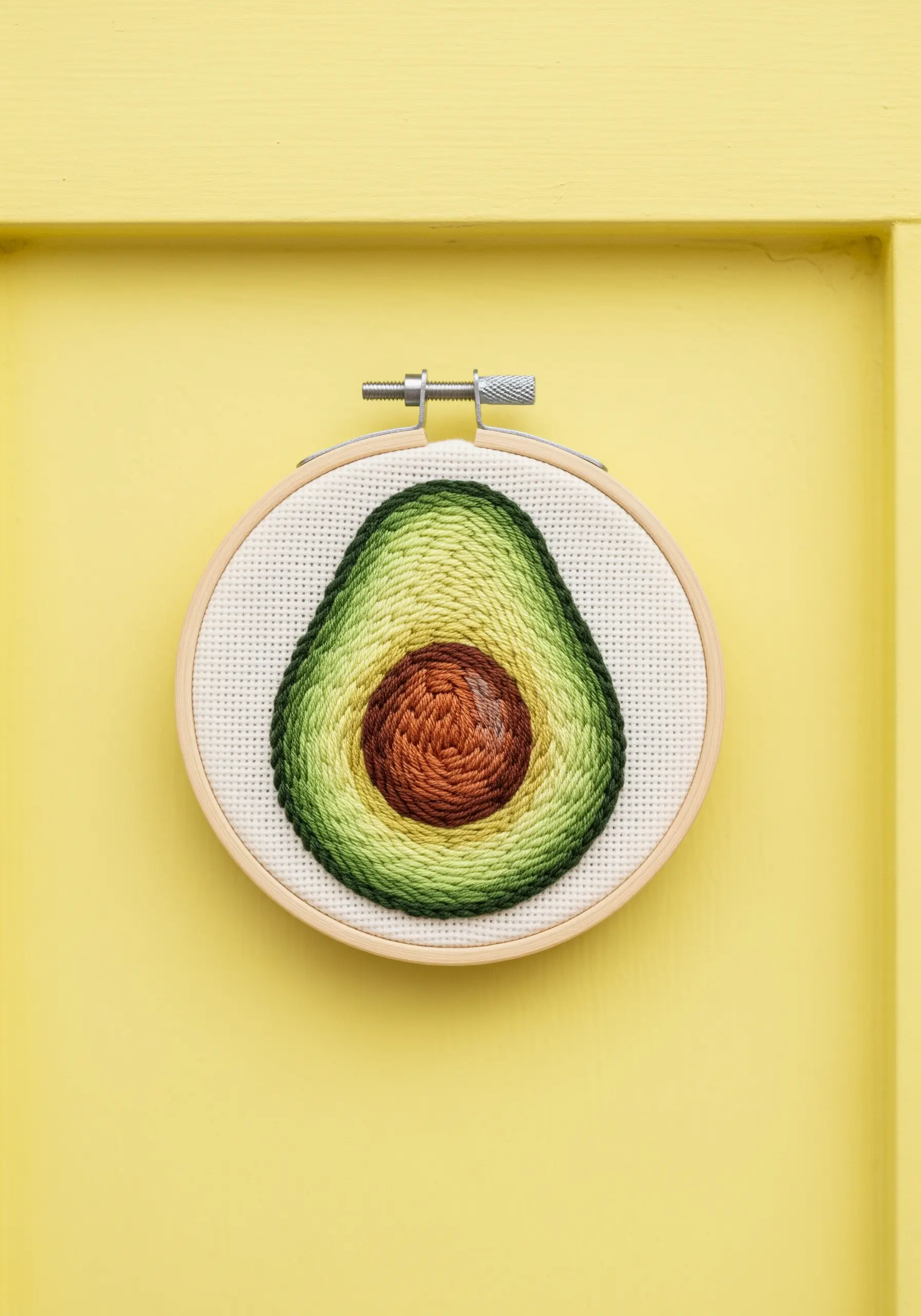 Embroidered avocado half with spiraling stitches to blend the colors of the pit and flesh.