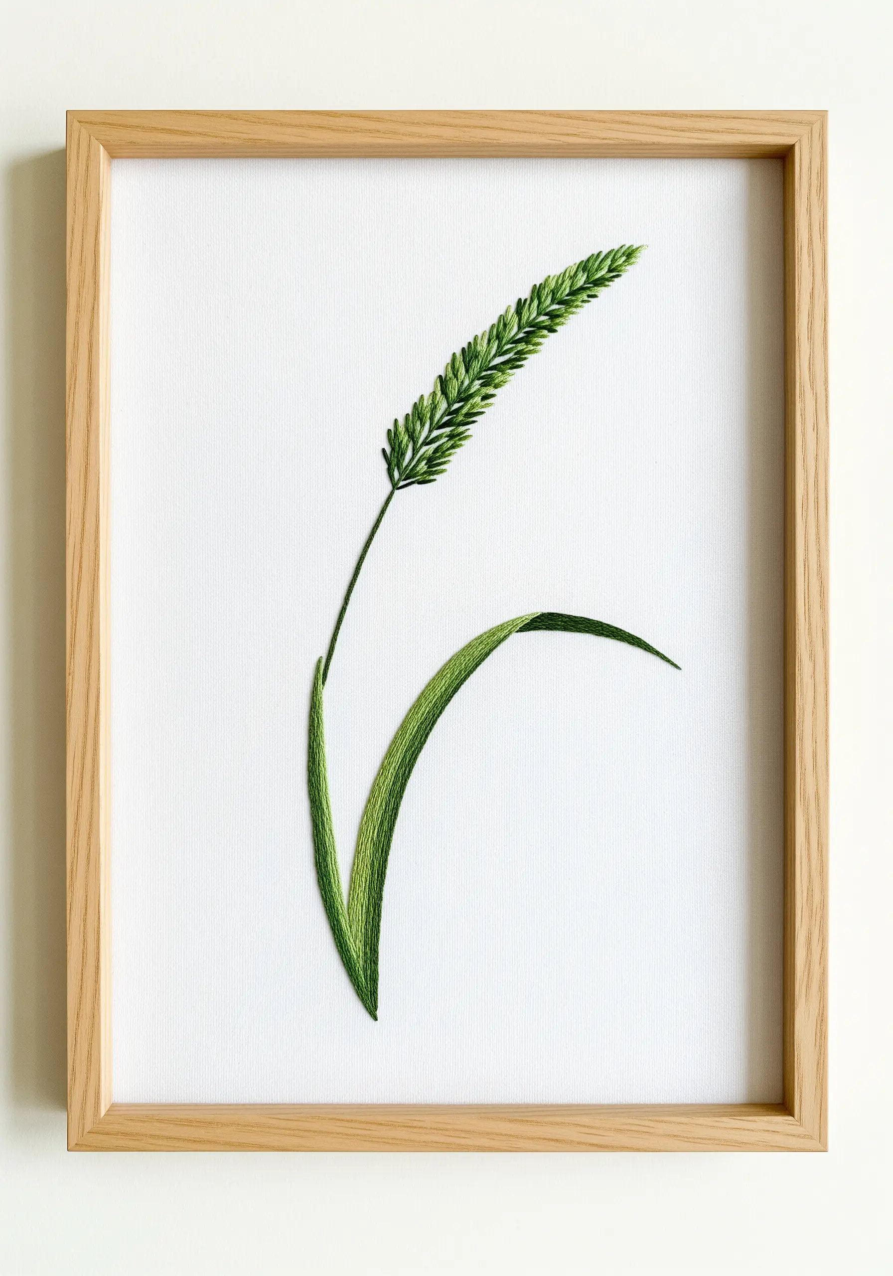 Framed embroidery of a single, realistic blade of grass using thread painting.