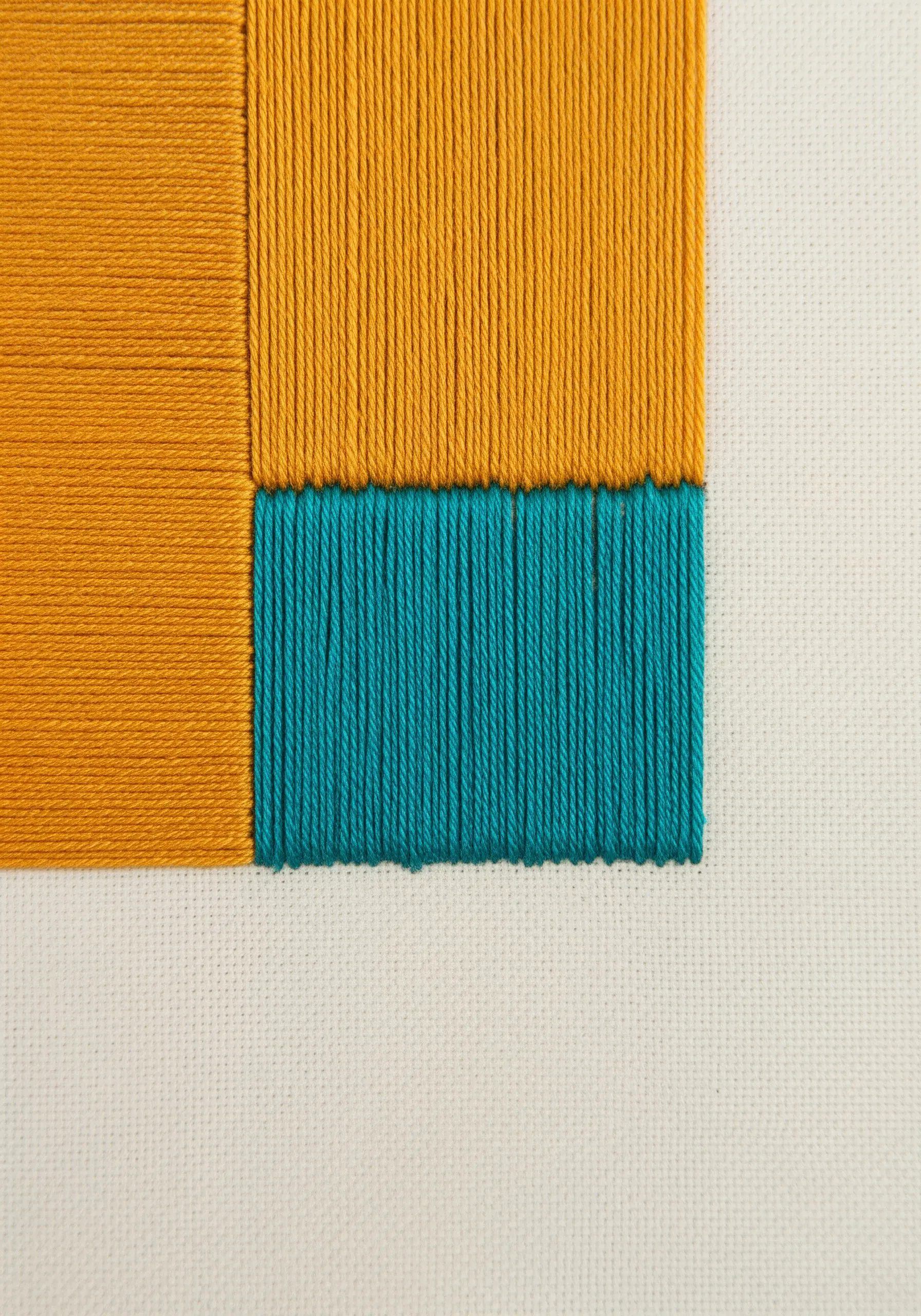 A close-up of perfectly executed satin stitch color blocking in yellow and teal.