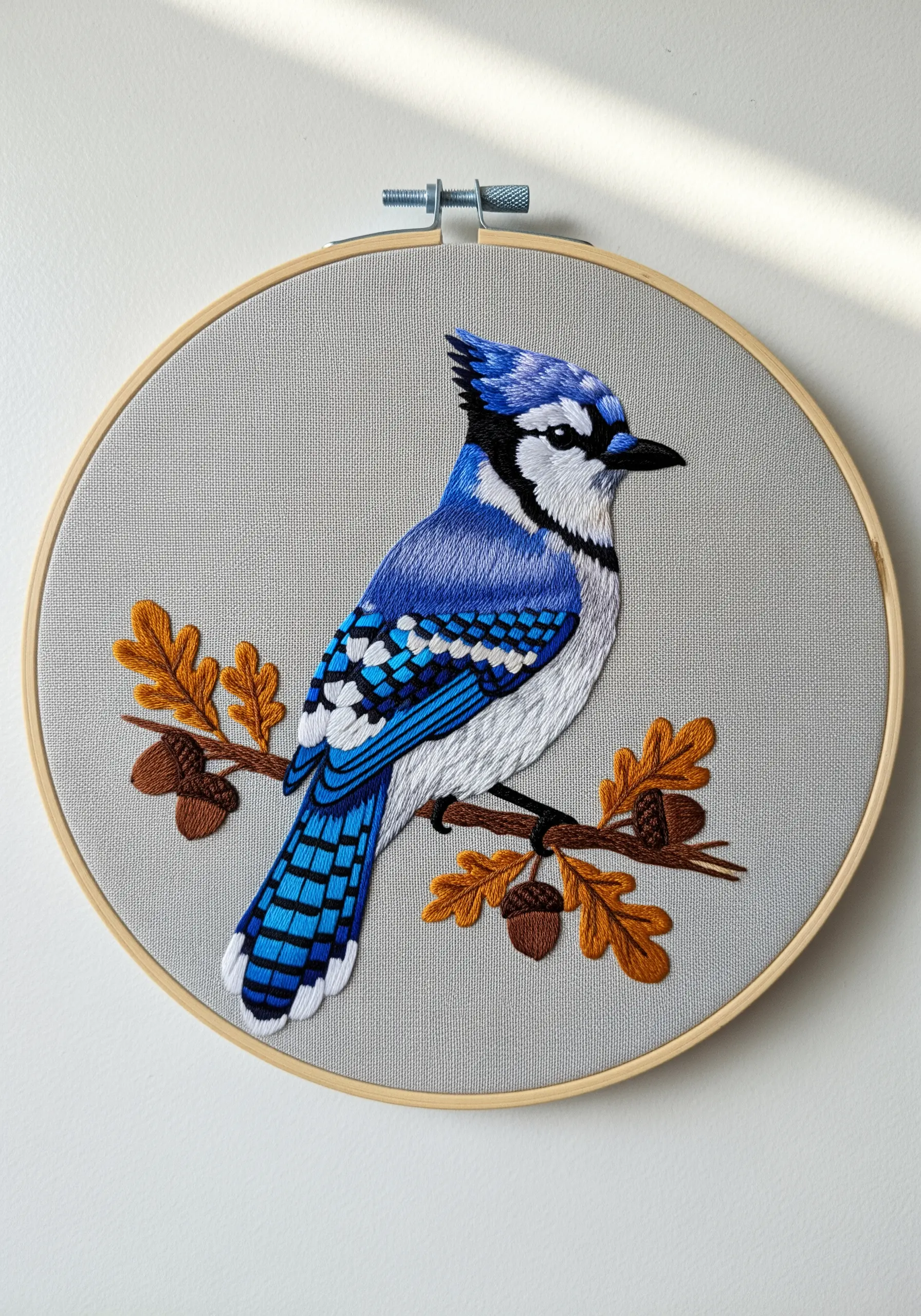 Blue jay embroidery with clean, bold satin stitch patterns on its wings.