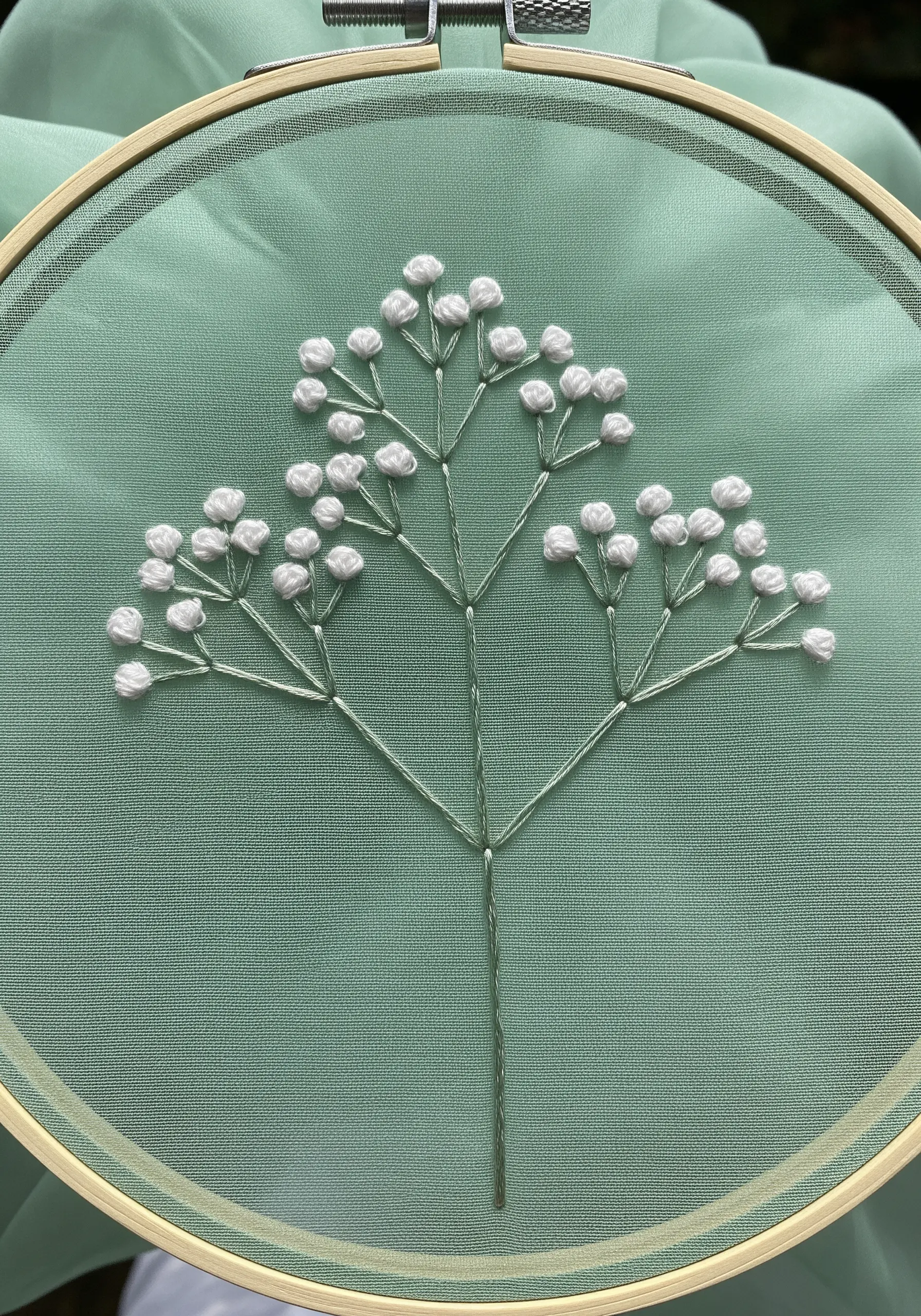 Delicate Baby's Breath embroidered with white French knots on a mint green fabric