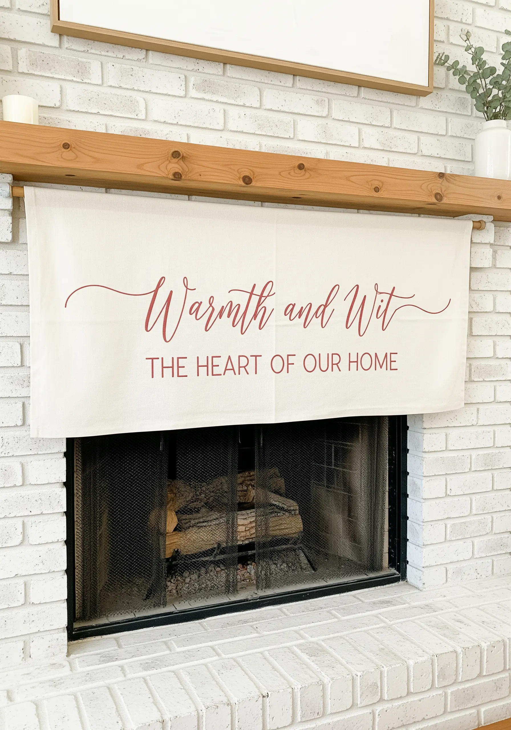 A fireplace banner with 'Warmth and Wit' embroidered in elegant dusty rose script.