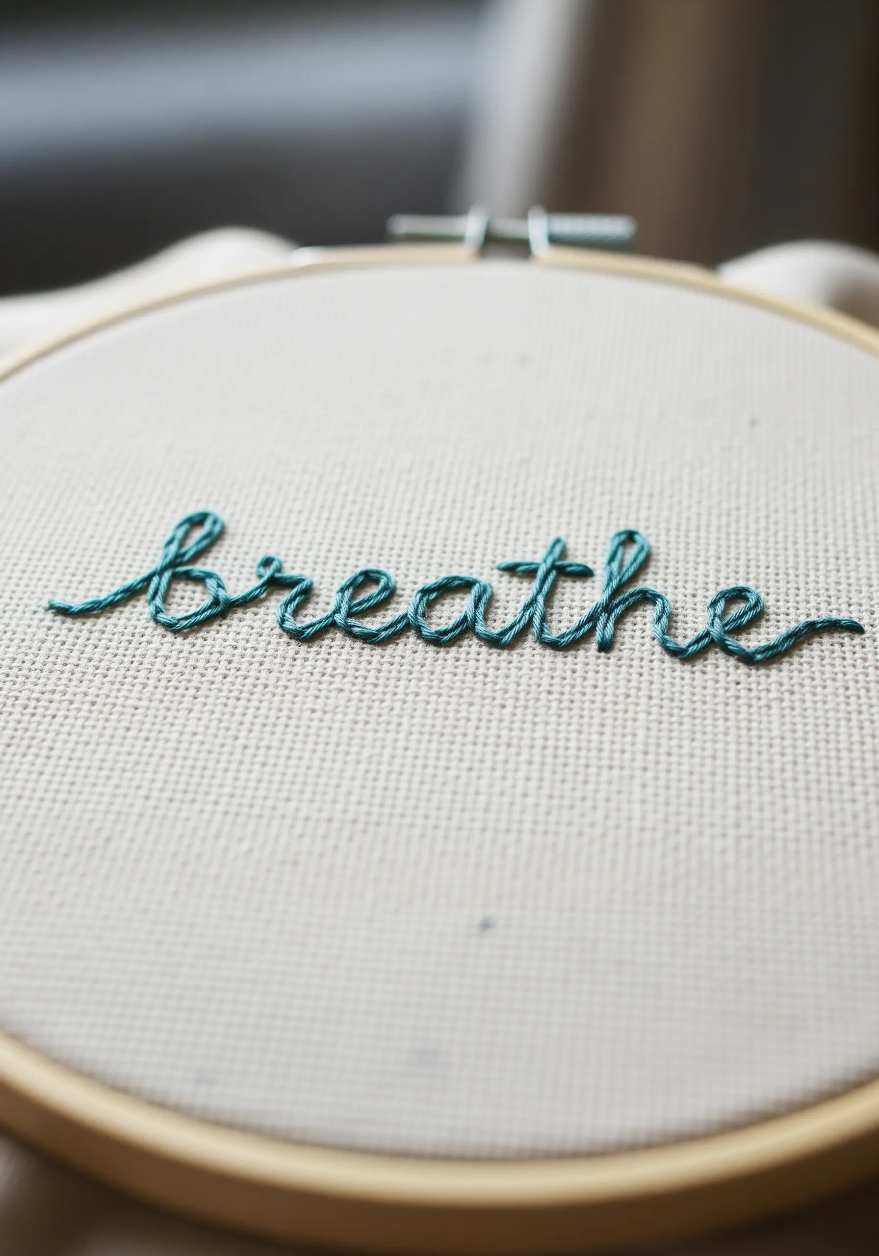 The word 'breathe' embroidered in teal using a smooth, continuous whipped backstitch.