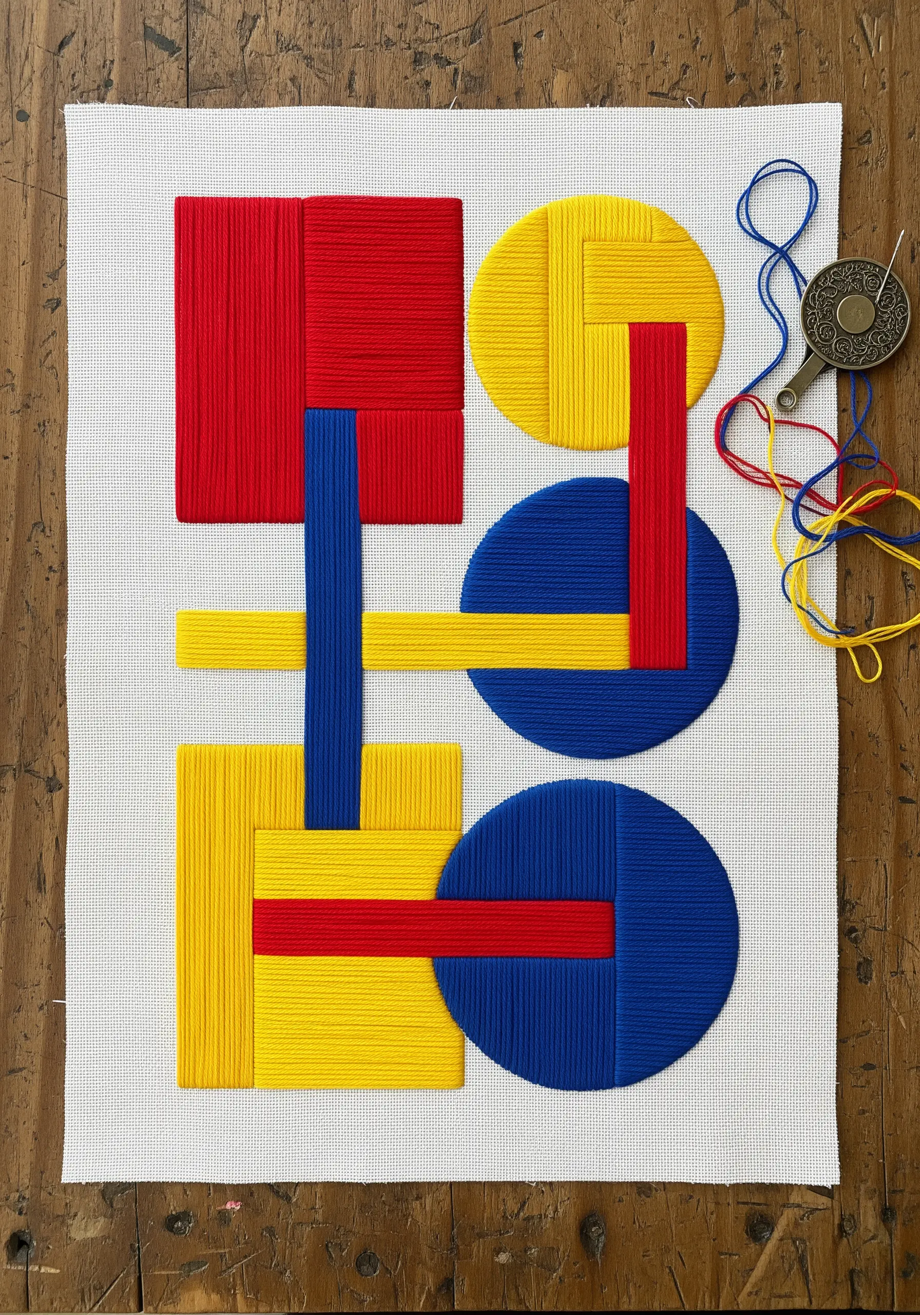 Geometric abstract embroidery with red, yellow, and blue wrapped thread shapes.
